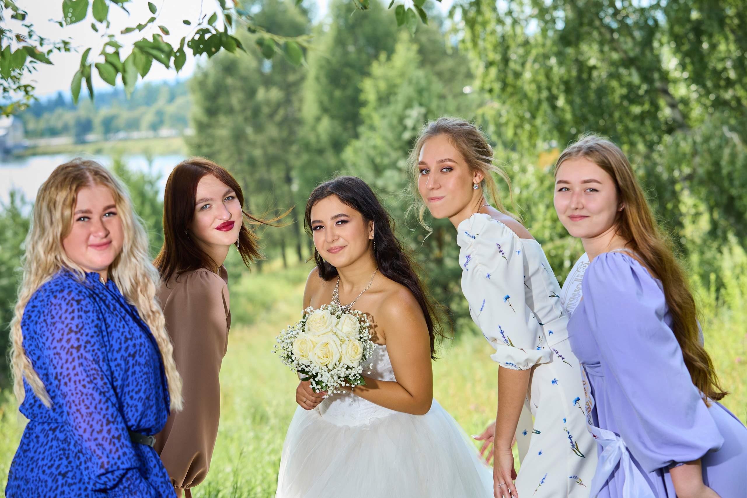 Невеста в свадебном платье с букетом в окружении подруг