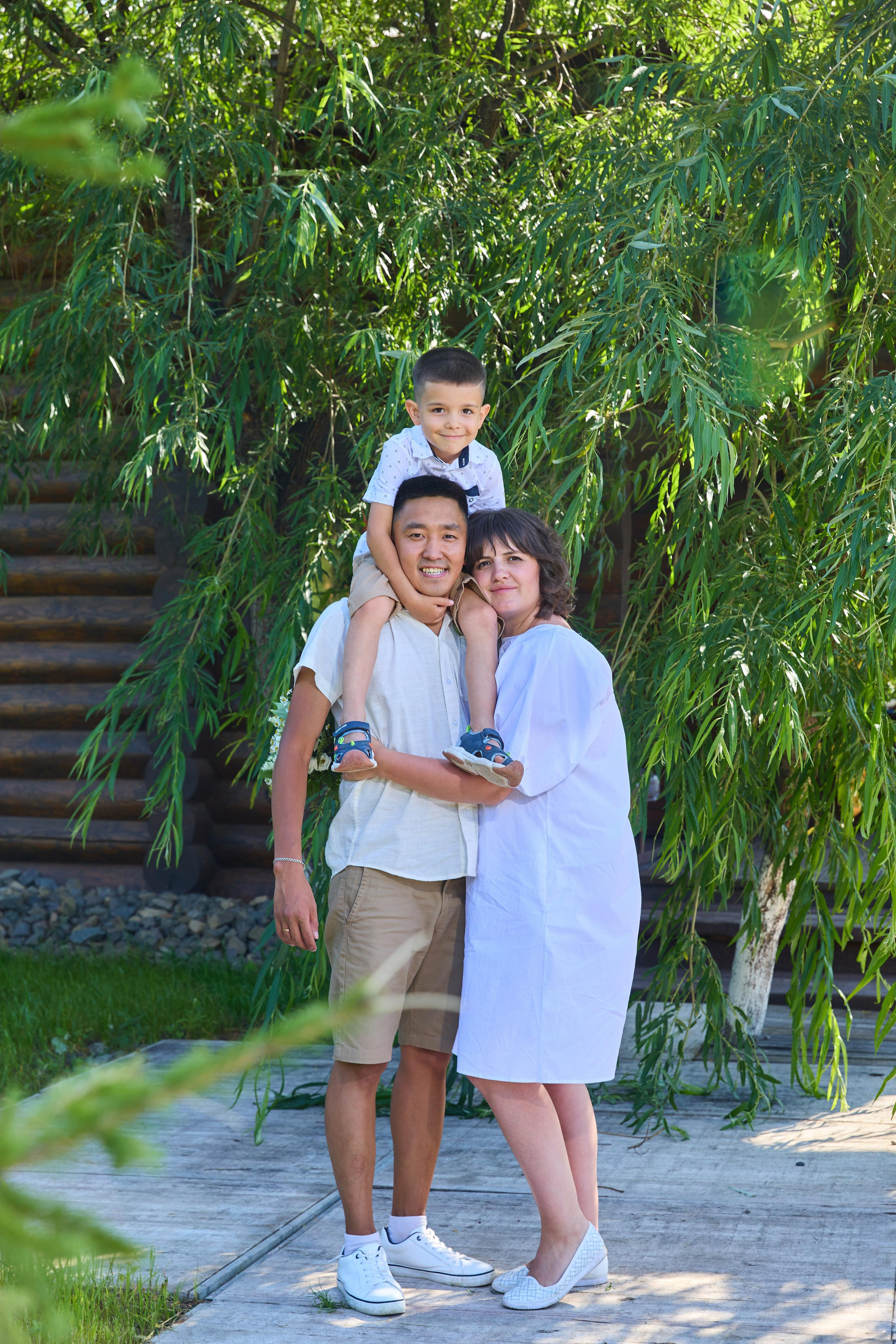 папа держит сына на плечах, рядом мама