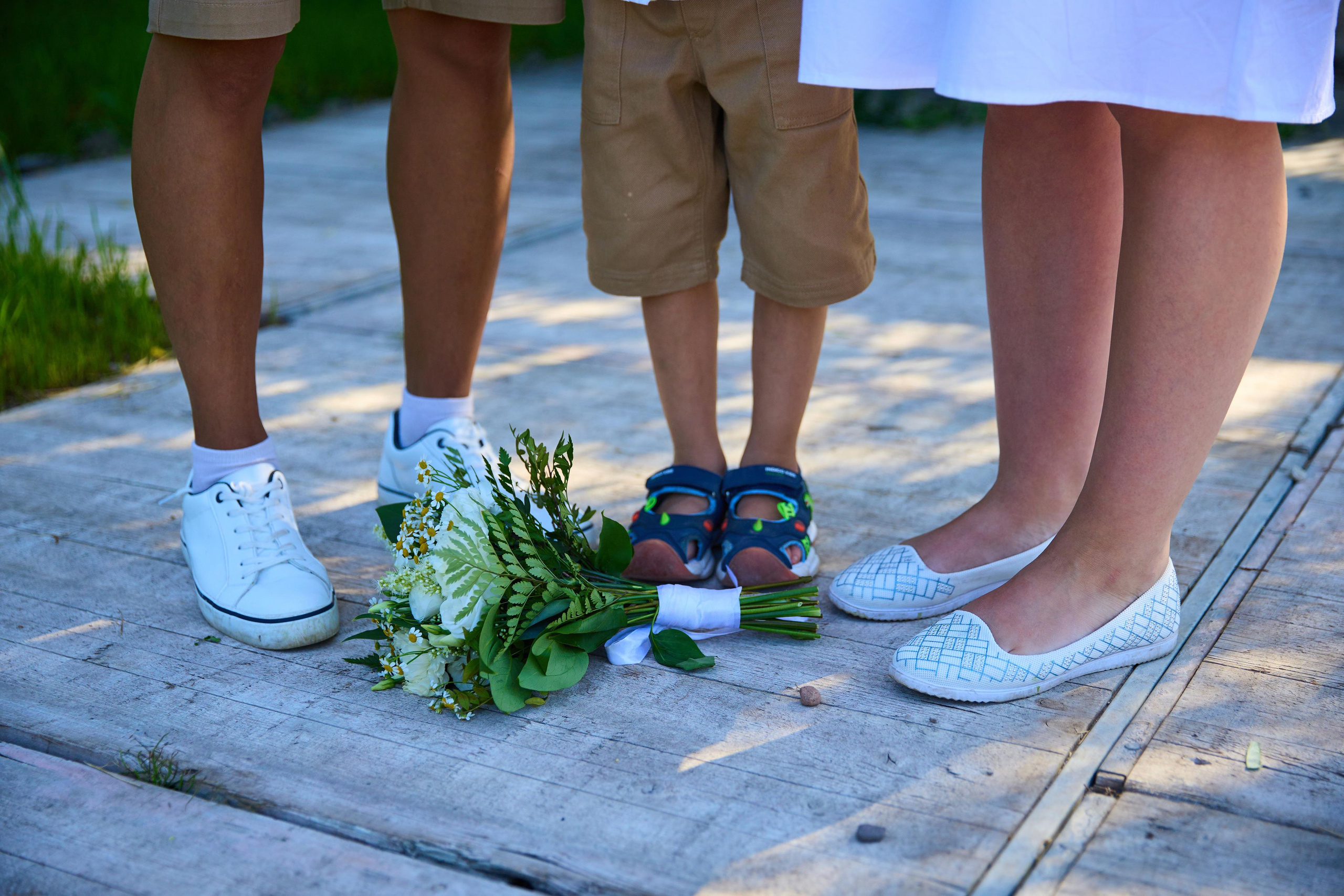 Три пары ног, на полу лежит свадебный букет