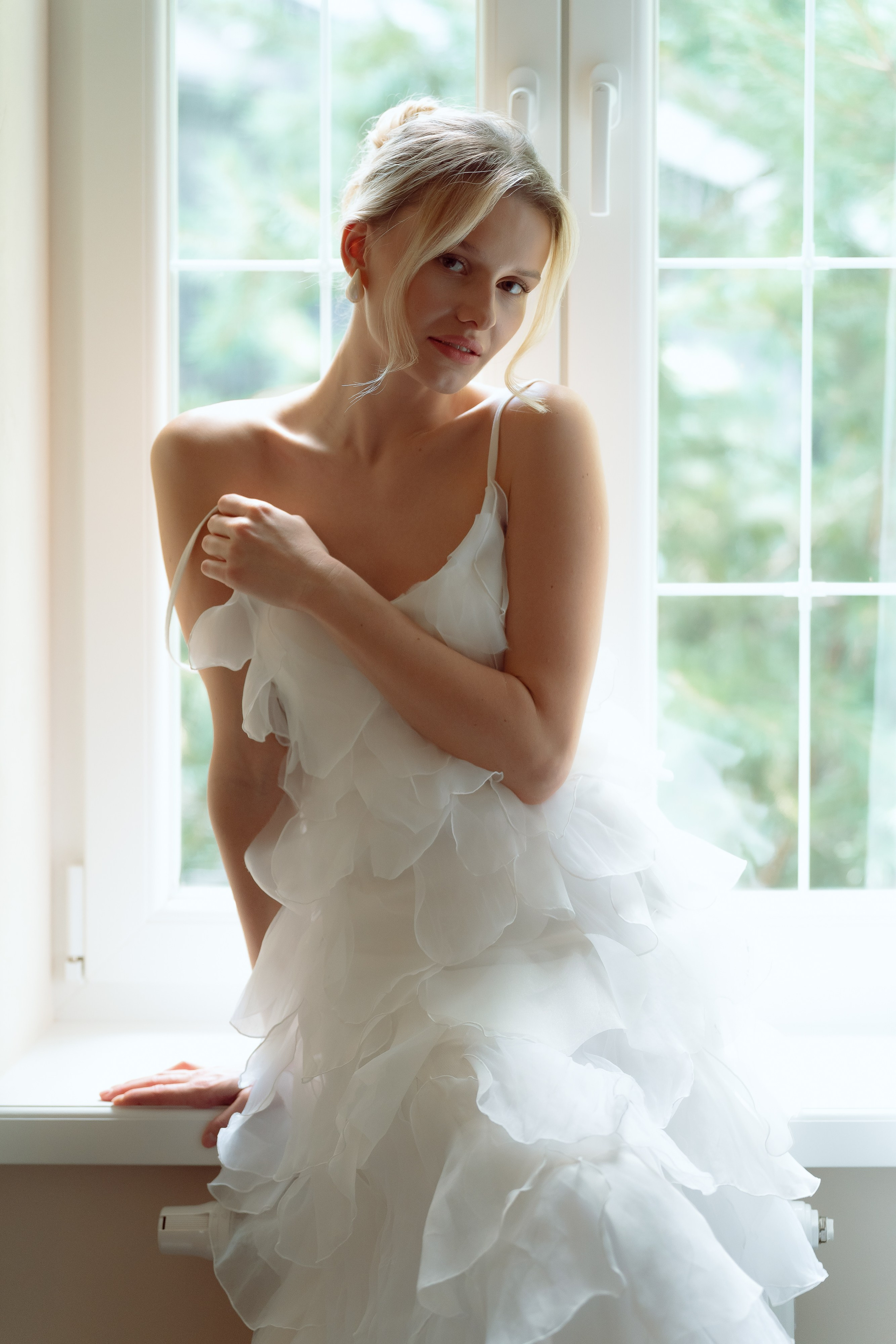 Улыбка невесты в свадебном платье у окна.