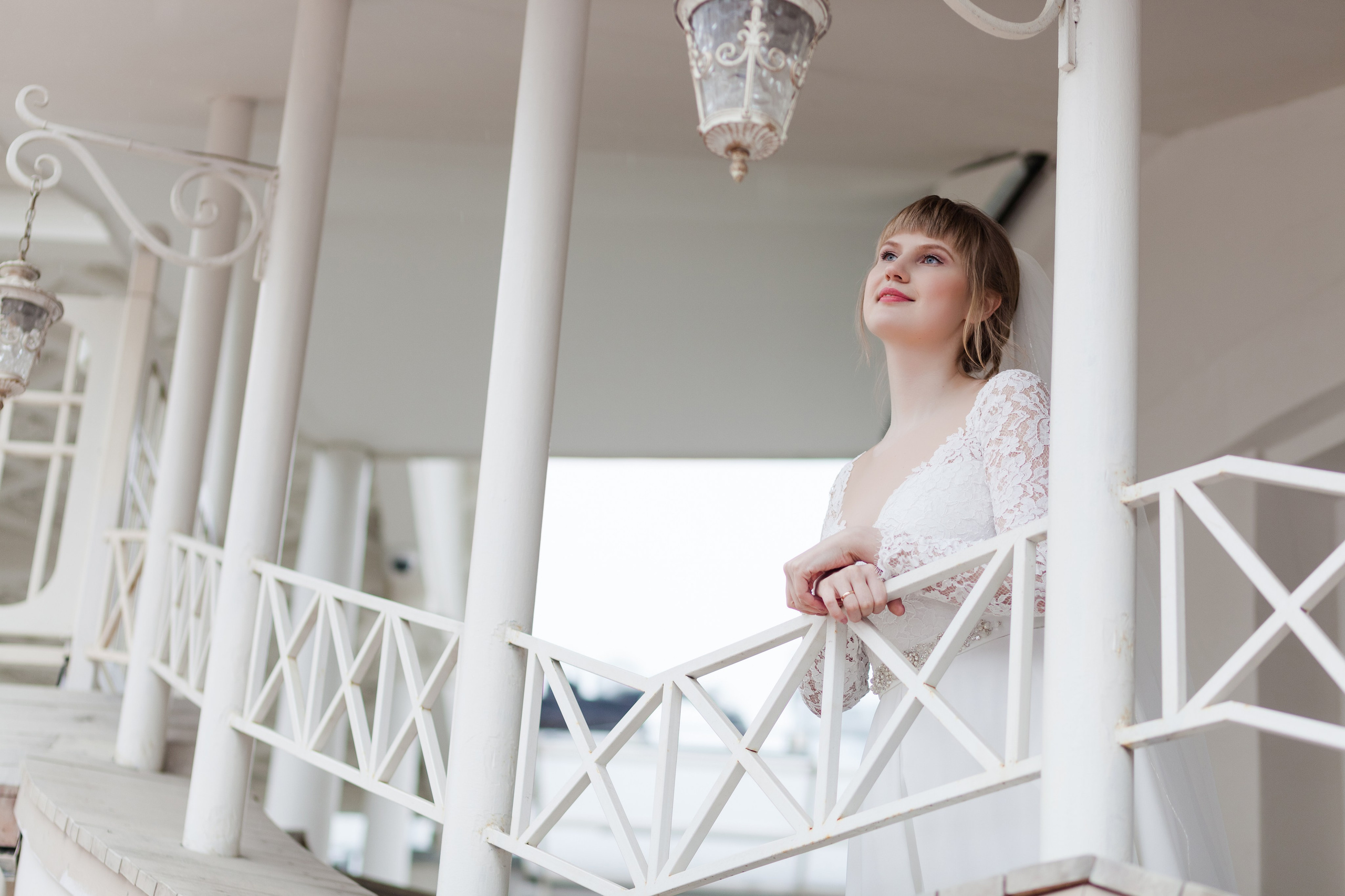 Невеста стоит на белом балконе ресторана