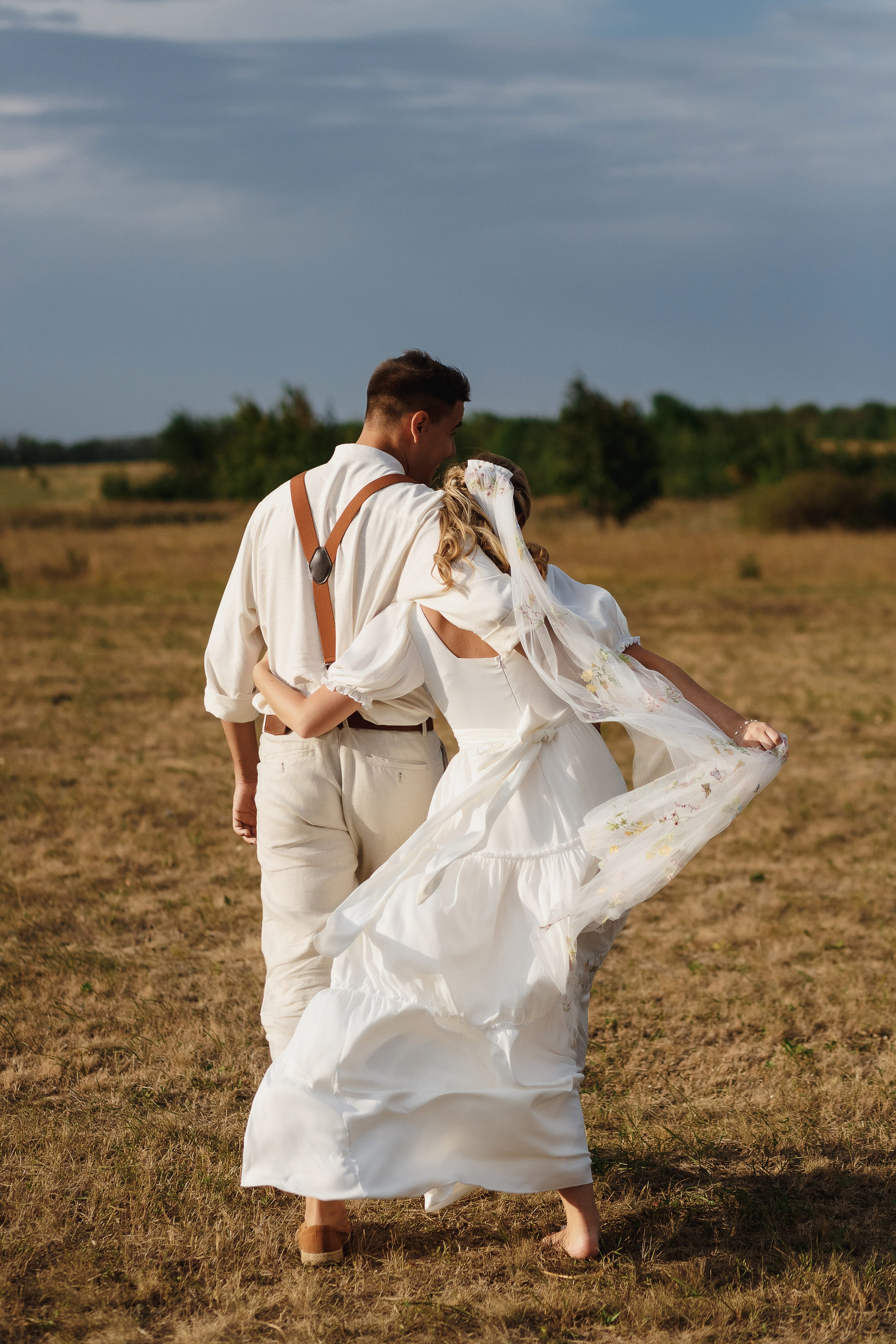 Молодожёны идут по полю, обнявшись — романтическая свадебная прогулка, фотограф Таганрог.