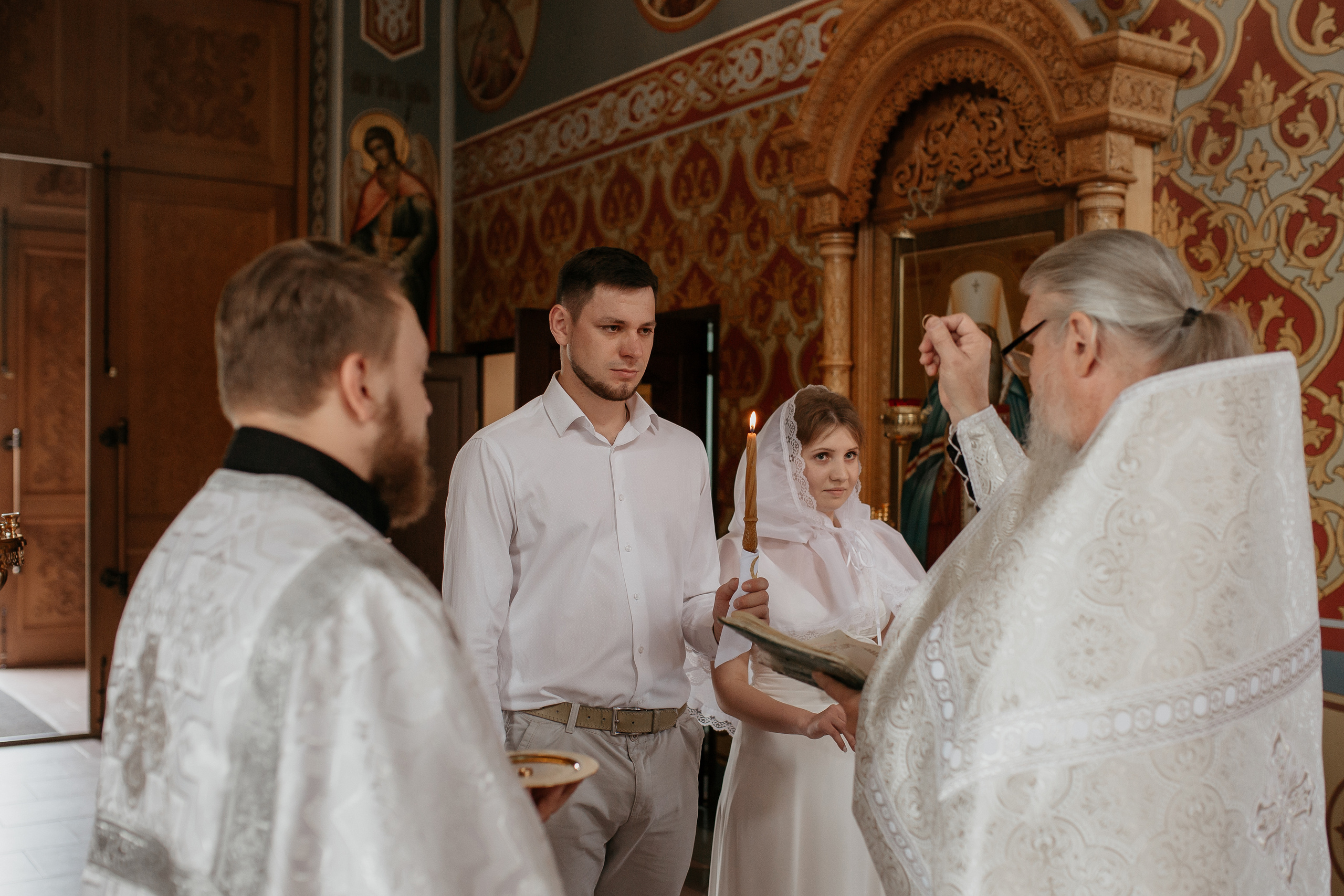 священник благословляет мужа и жену кольцами в Ташкенте