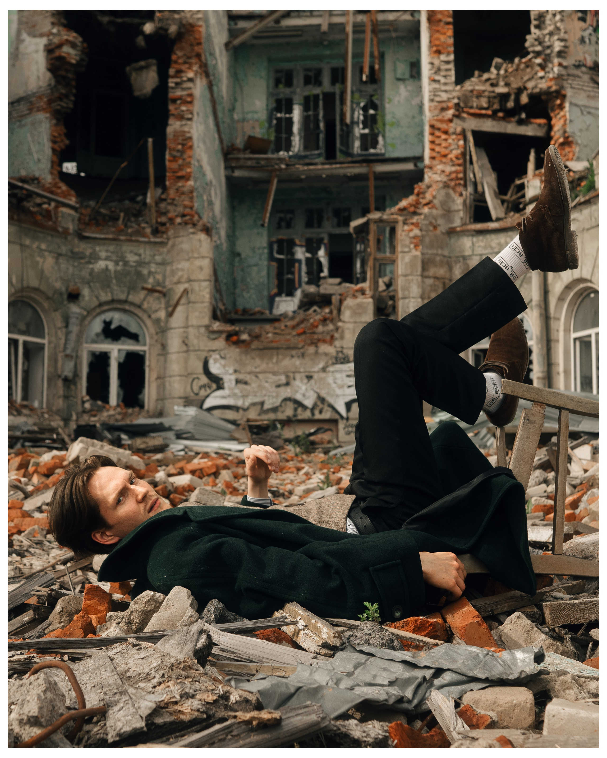 Портрет лежачего мужчины на фоне разрушенного здания