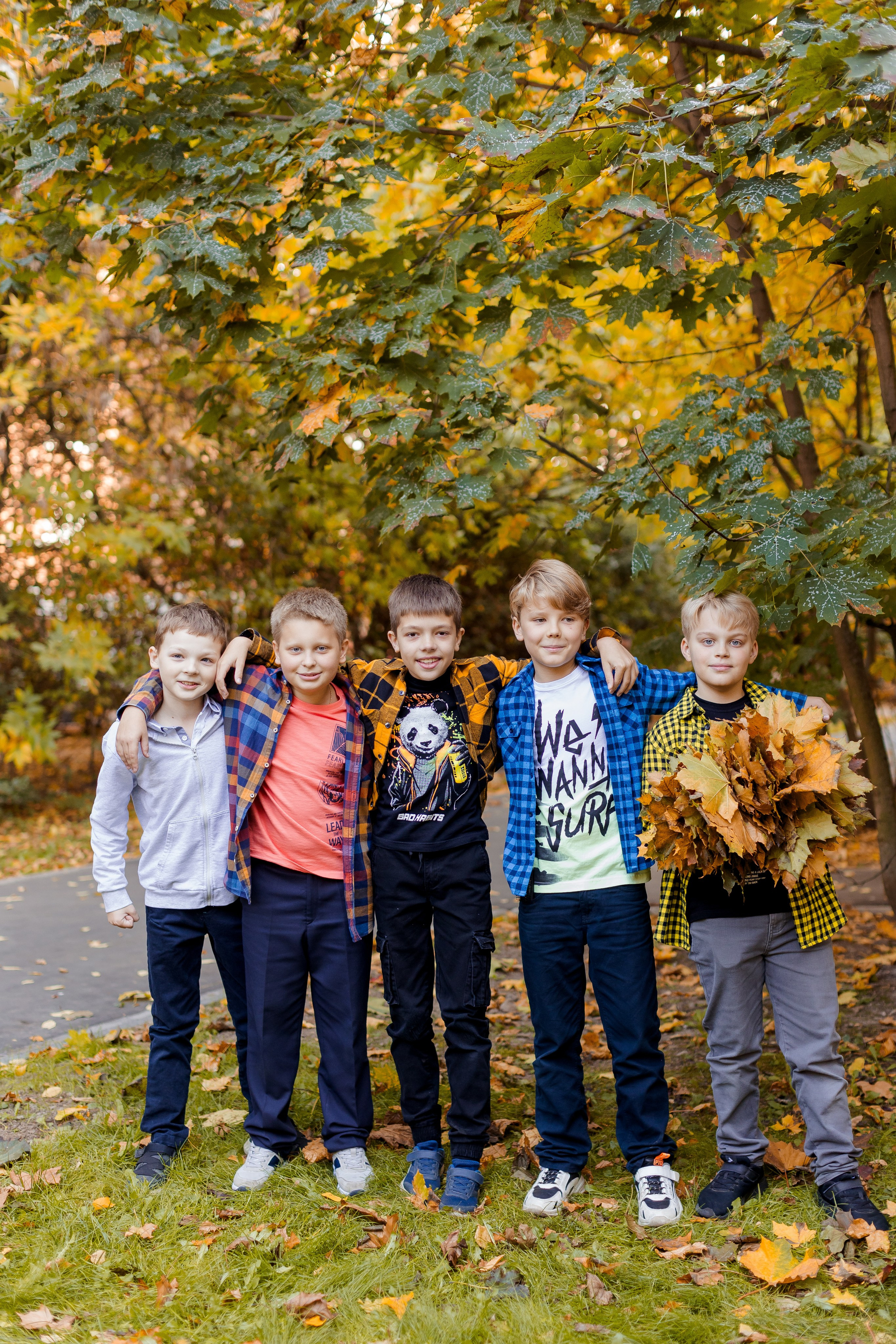 Мальчики друзья позируют на фоне осеннего парка