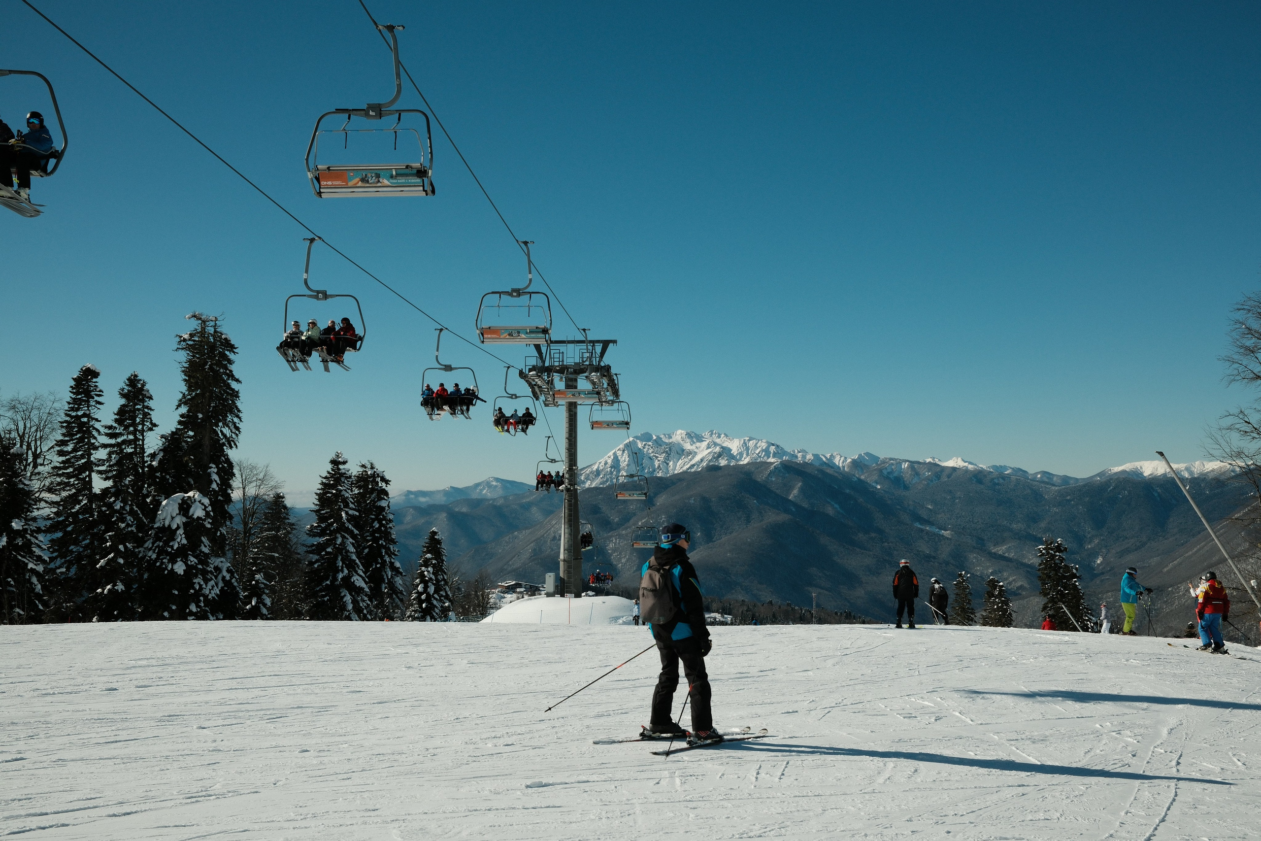 Горнолыжник едет по склону Лауры на фоне подъемника