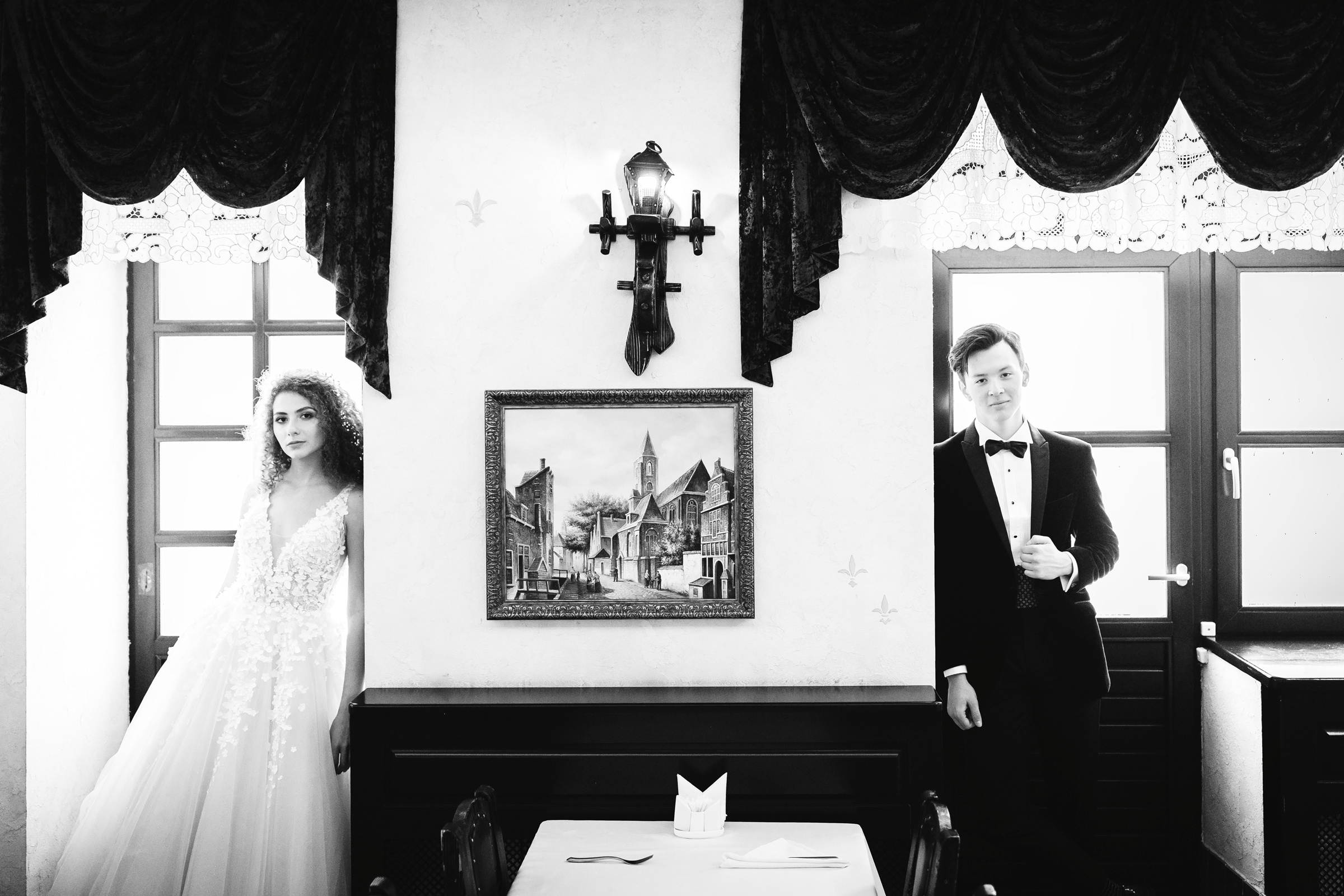 Молодожены позируют у окна 