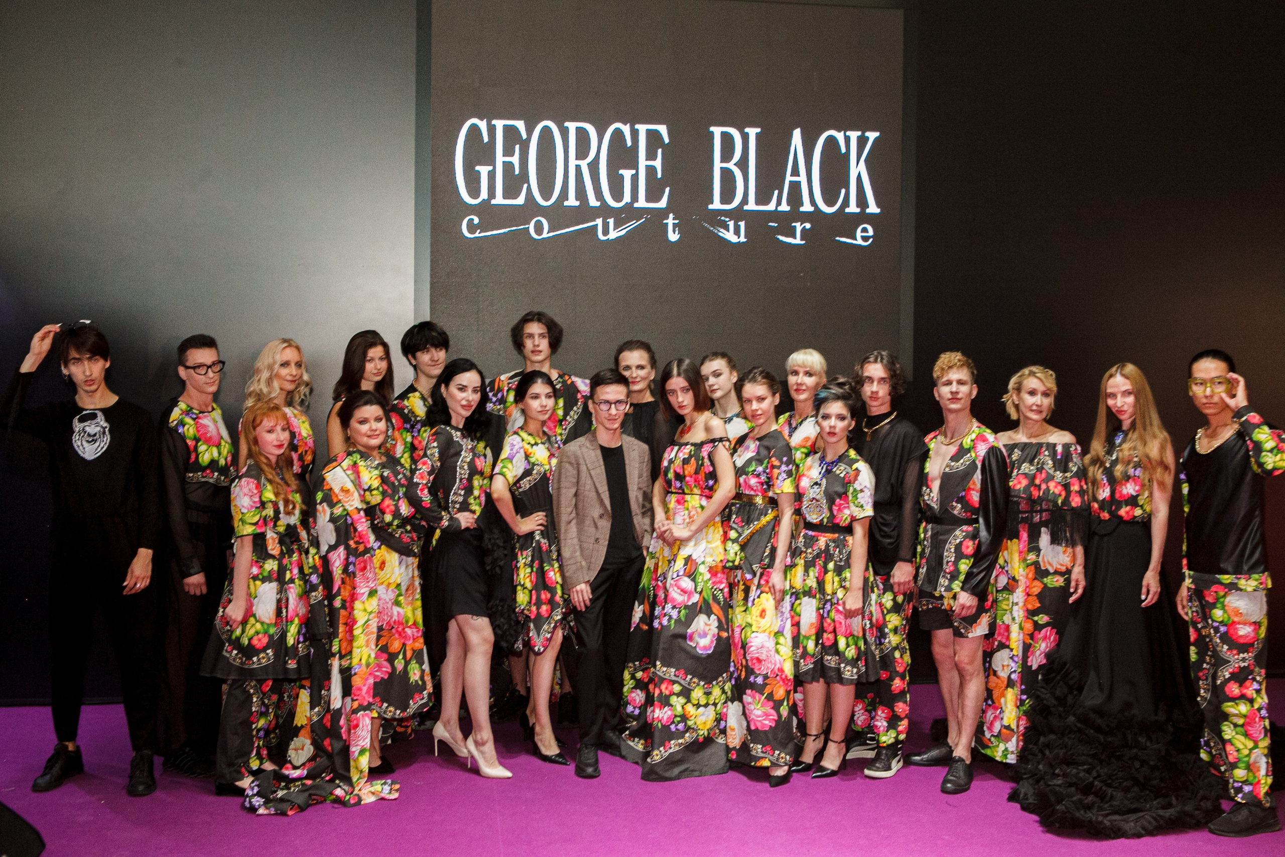  "Модели в ярких нарядах проходят по подиуму во время показа мод, освещенные яркими софитами и окруженные восторженными зрителями."