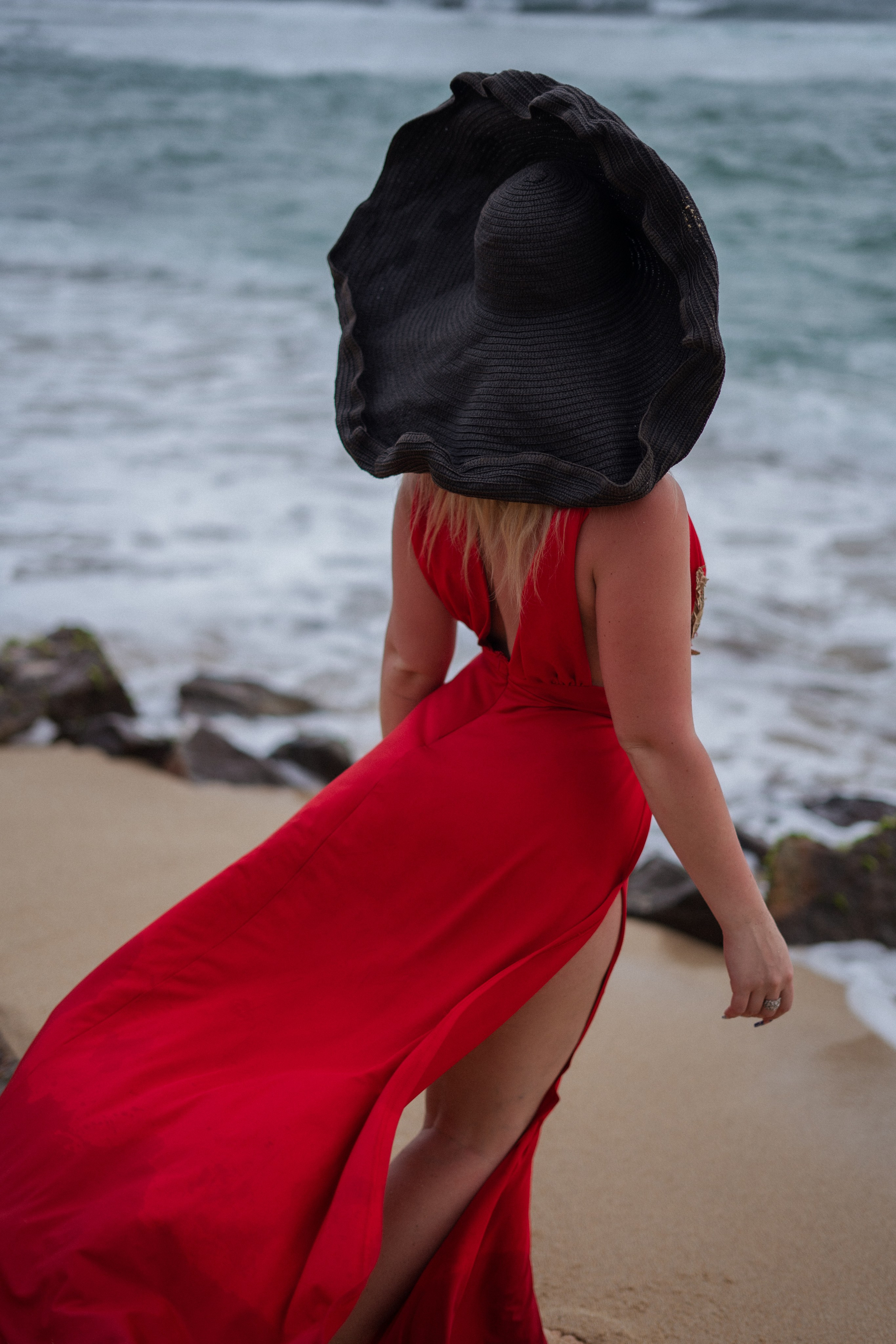 a beautiful blonde in a red dress against the sunset by the ocean