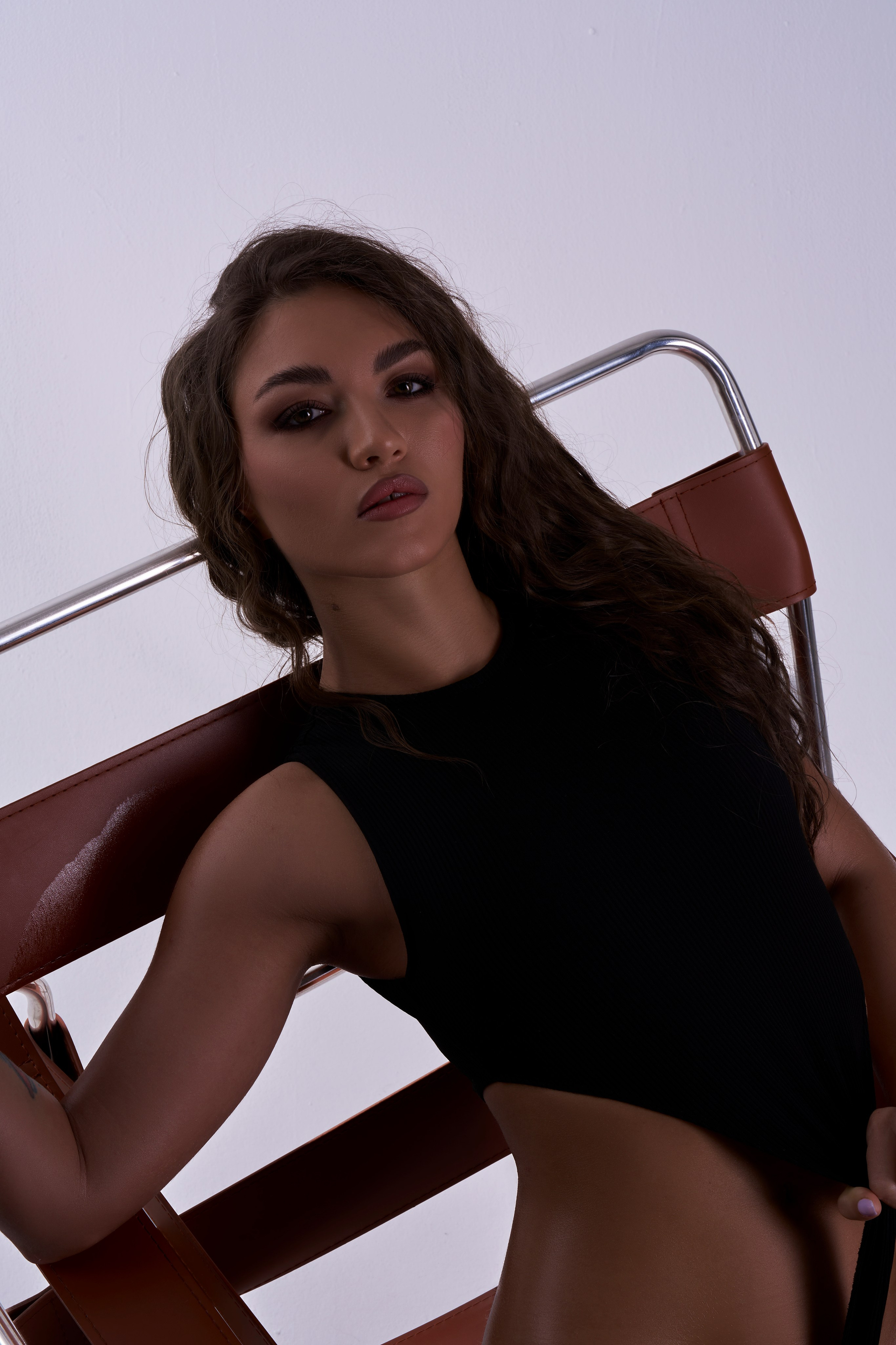 Портрет девушки с распущенными волосами, макияж и выразительный взгляд, ню-фотосессия на стуле в Москве.