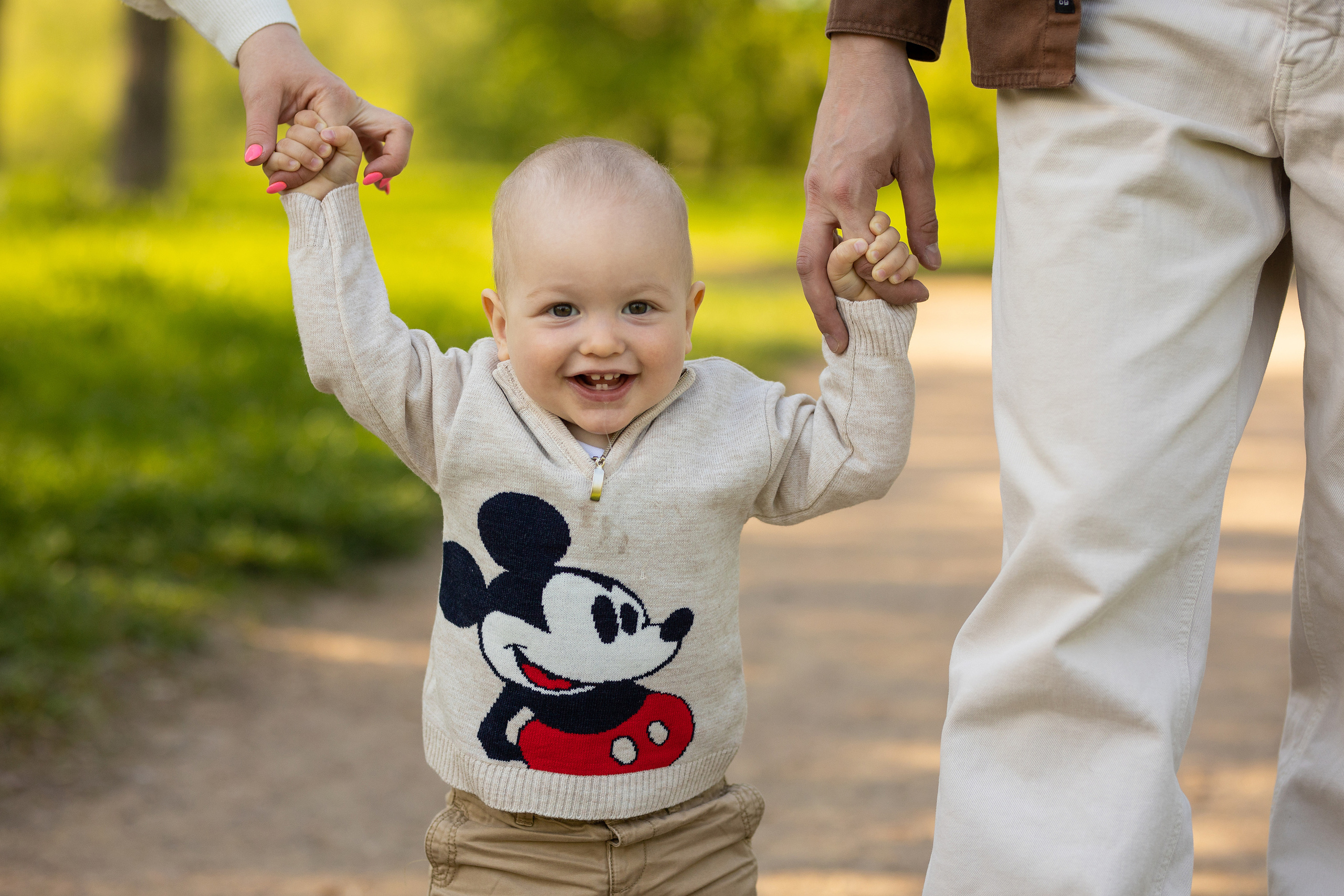 родители держат малыша за руки