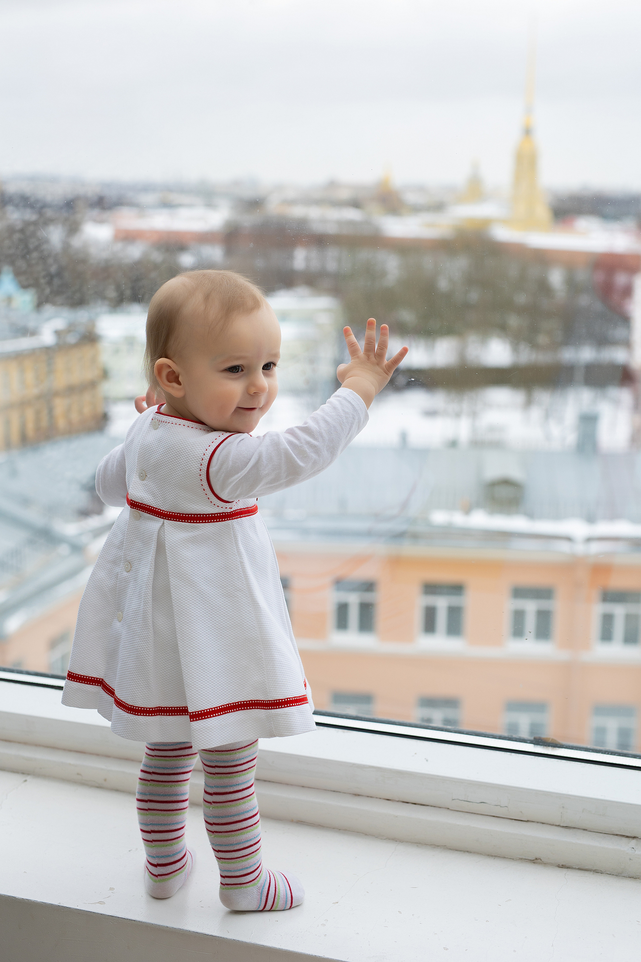 девочка смотрит в окно на город