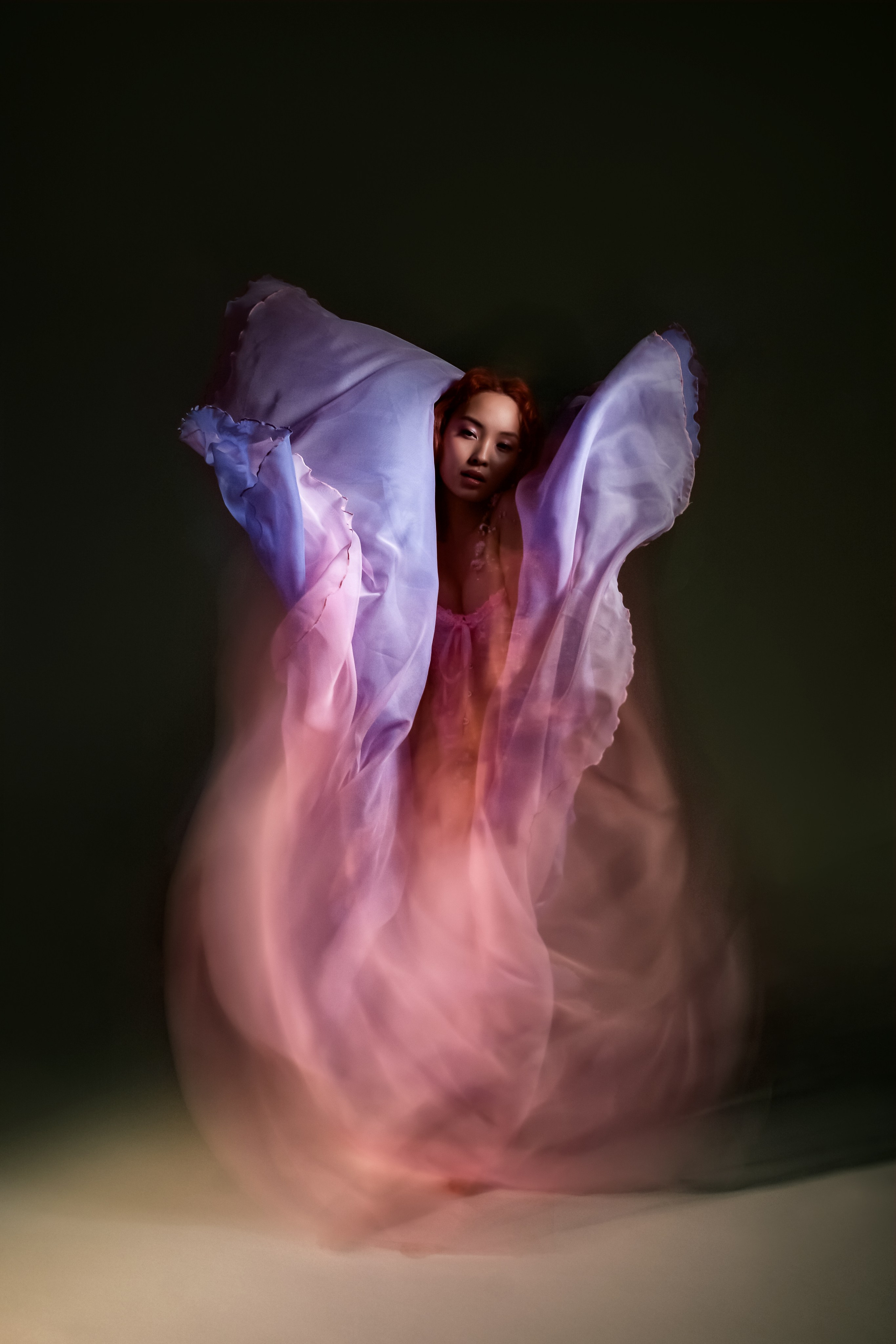  Портрет юной красавицы, воплощающей образ распустившегося весеннего цветка. На девушке пышное розовое платье, а ее шея и запястье декорированы свежими цветами. Мягкое смешанное освещение придает кадру романтичную атмосферу.