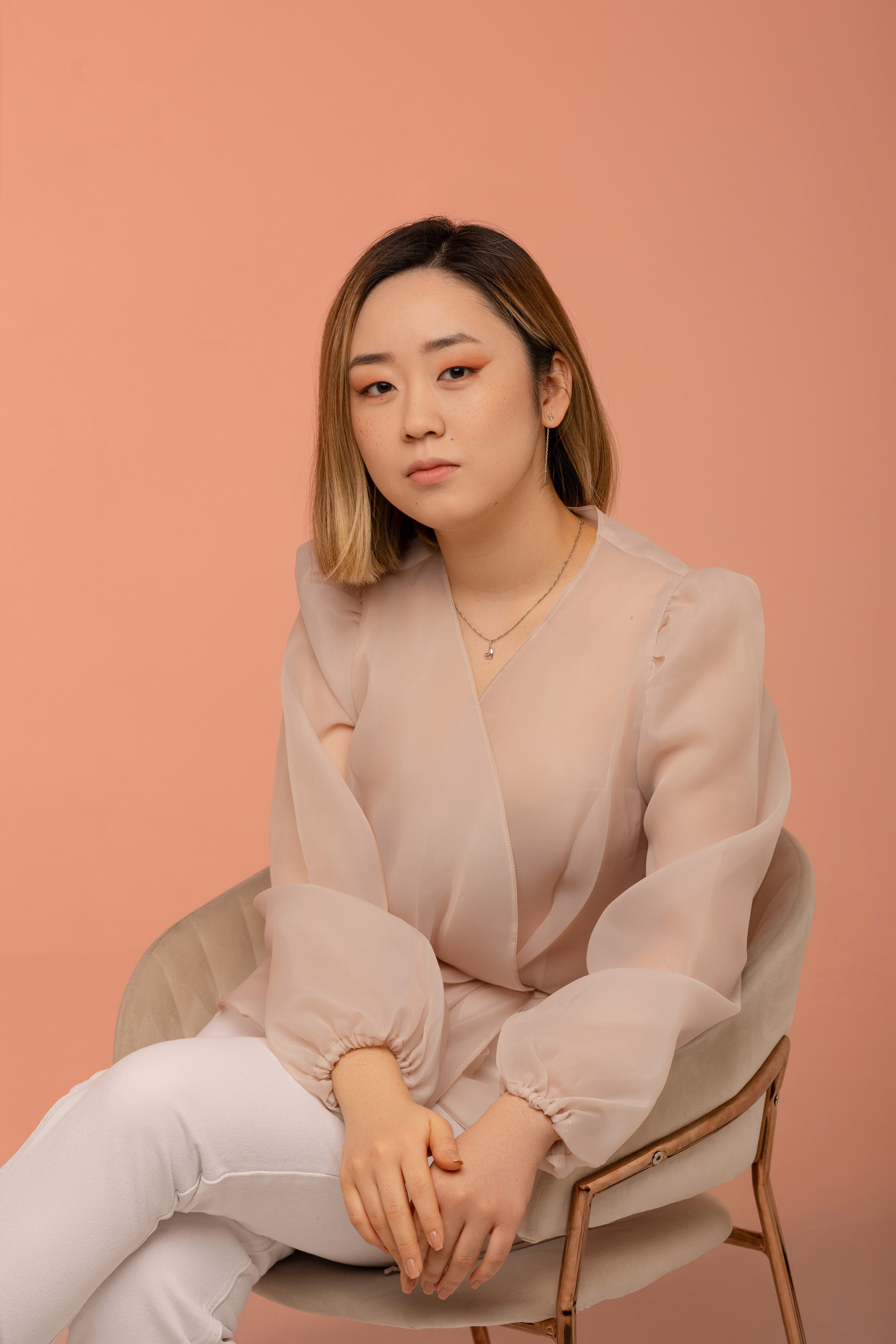 Девушка сидит в кресле, положив ногу на ногу.