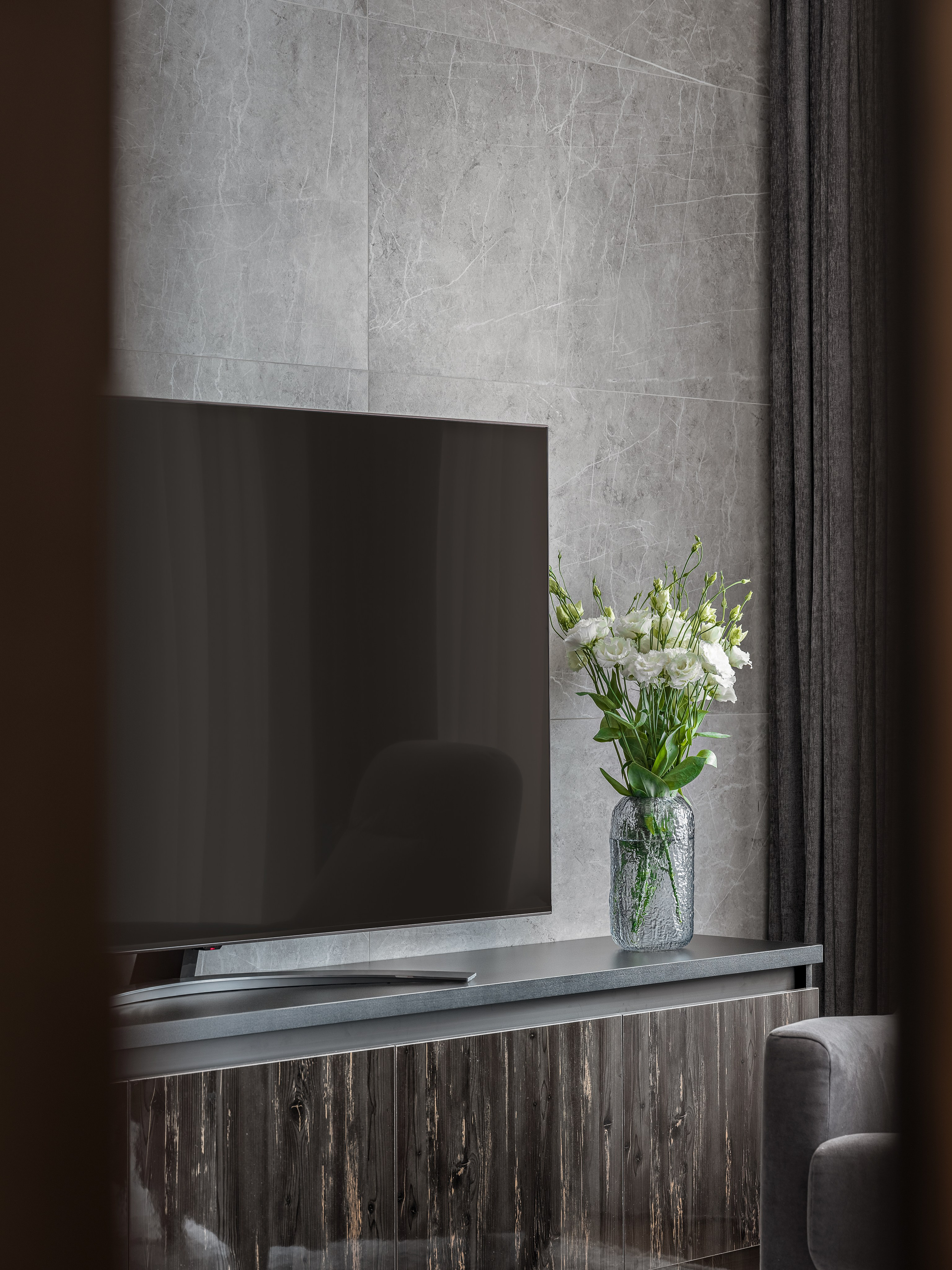 Деталь телевизионной зоны в гостиной с каменной стеной и стильной вазой с цветами, интерьер Алёны Поповой и Анастасии Дмитриевой, профессиональное фото Сергея Денисенко.