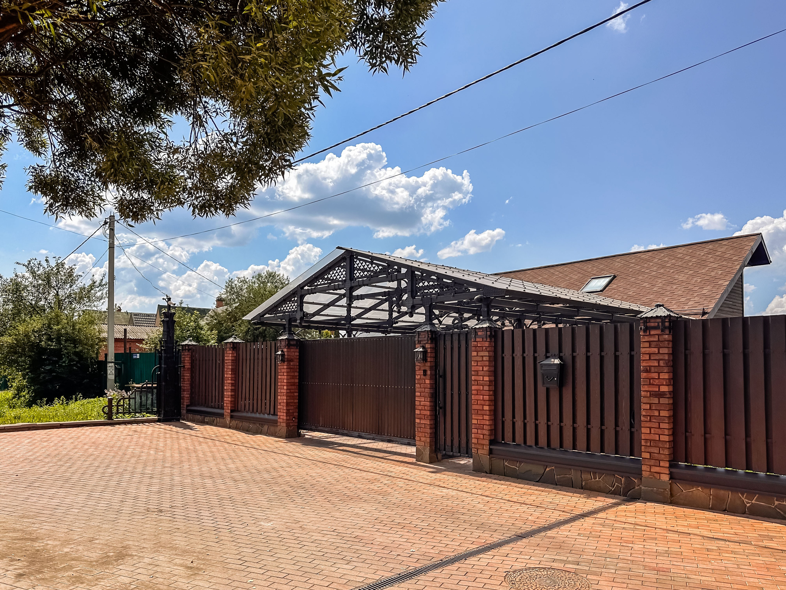 Общий вид комплекса — гараж, забор, ворота и мощёная площадка. Единый архитектурный ансамбль в стиле Лофт