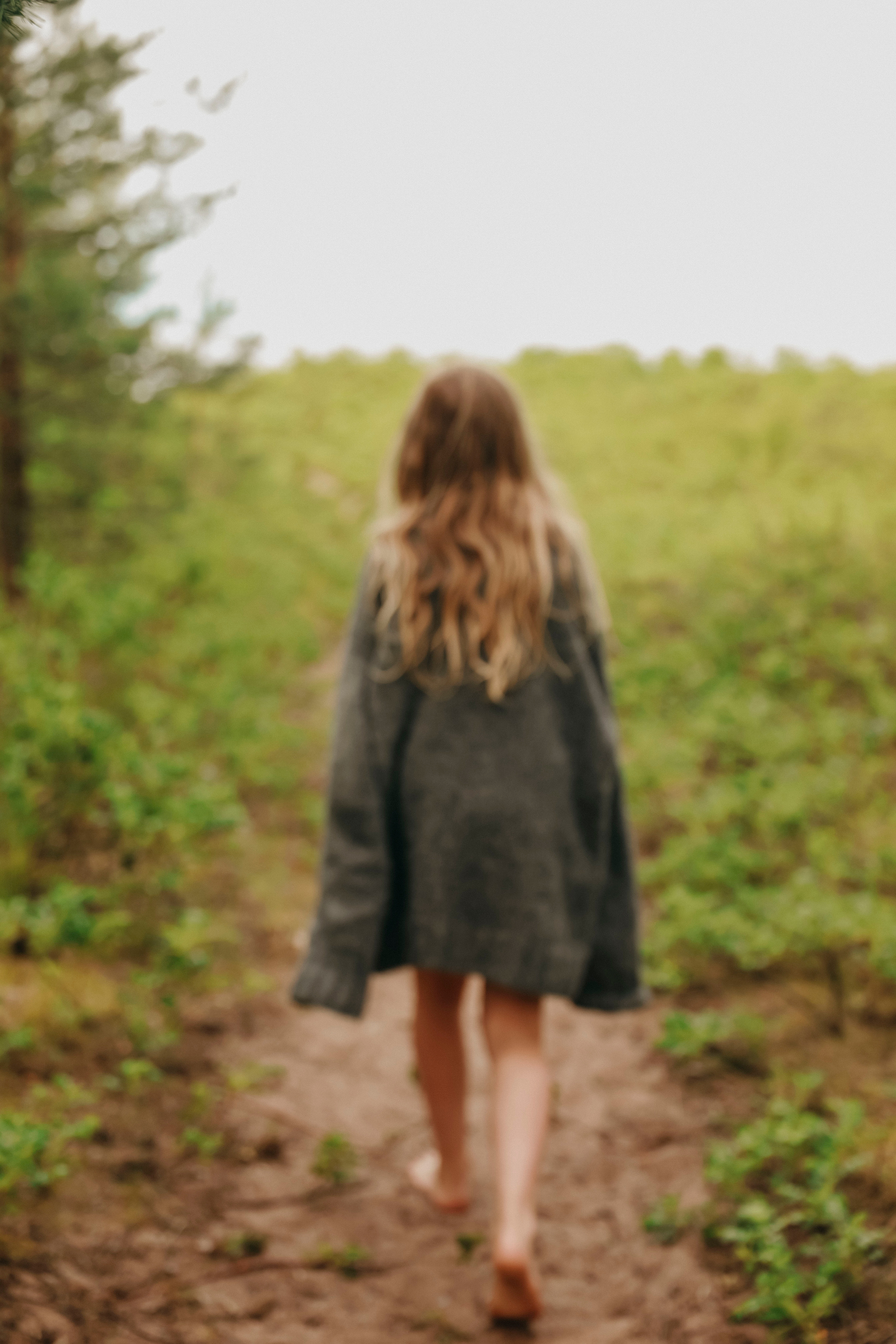 маленькая девочка в свитере идет по берегу моря