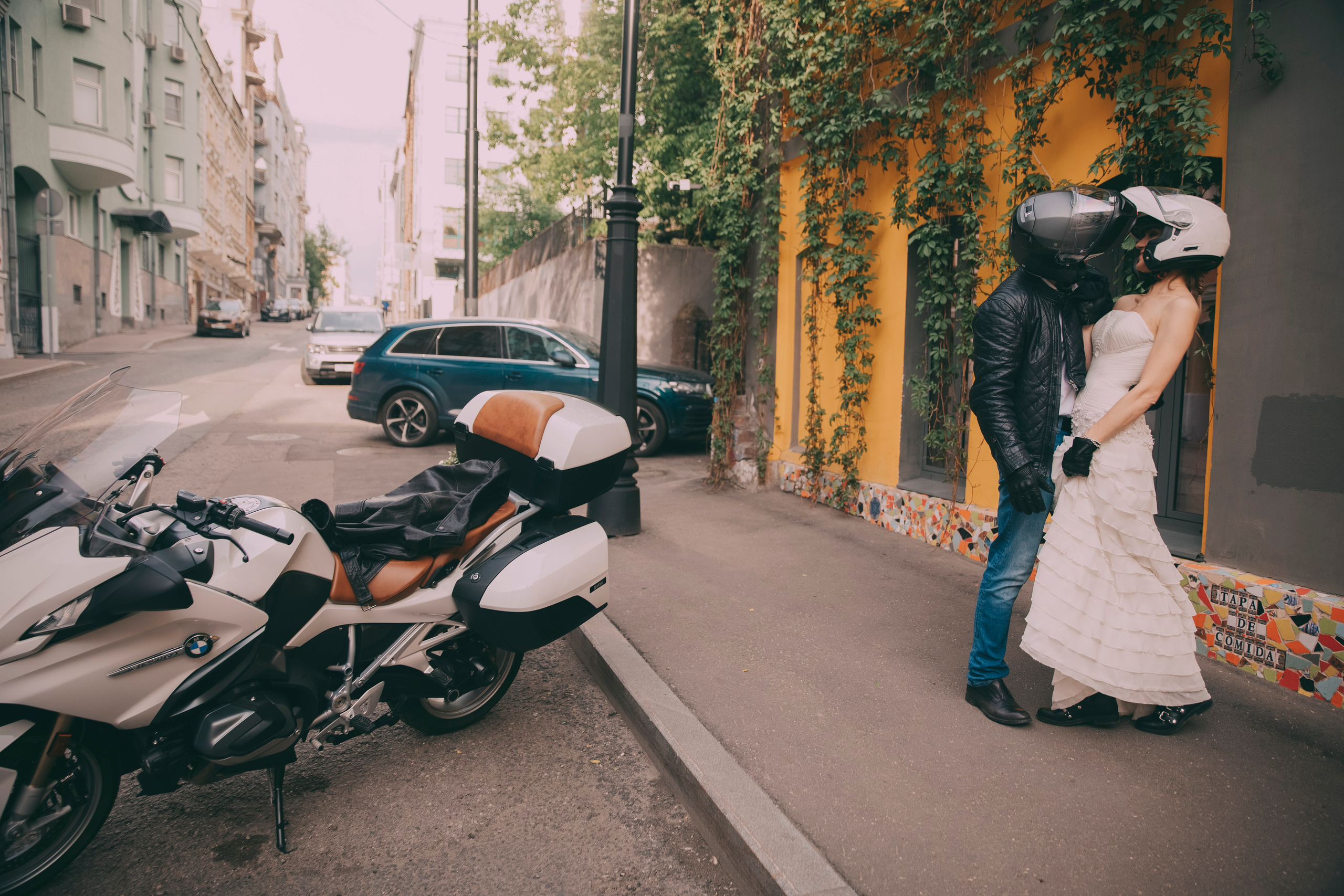 Молодожены целуются в шлемах для мотоцика  на улицах Москвы