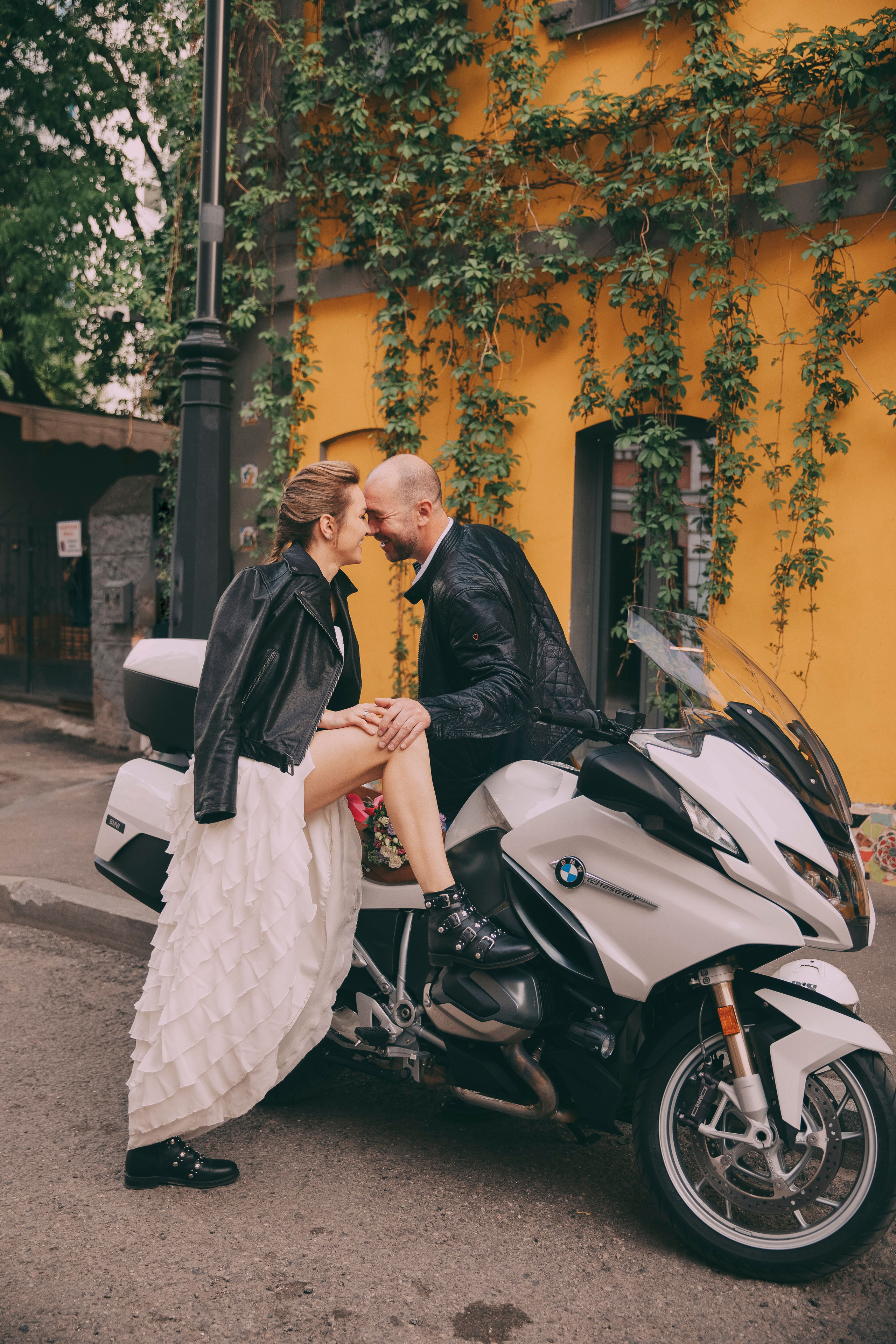 Невеста и жених целуется на мотоцикле  на улице города Москва
