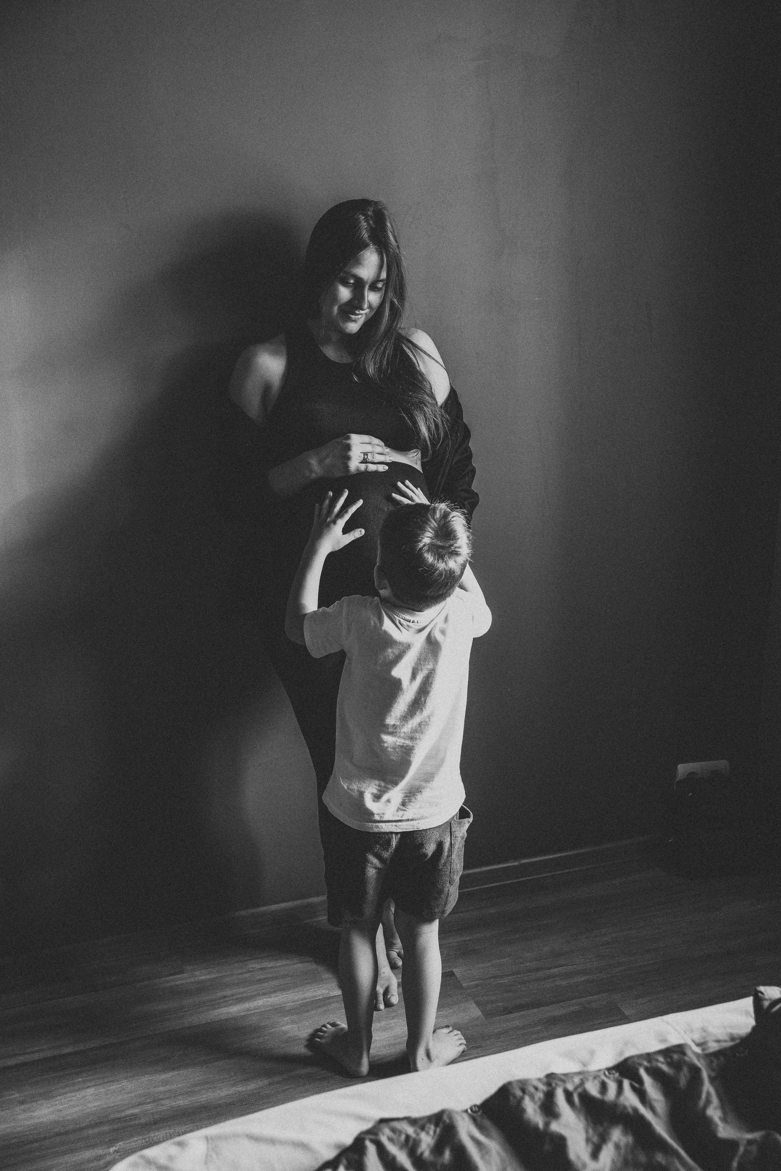 красивая беременная мама стоит в компании своего маленького сына