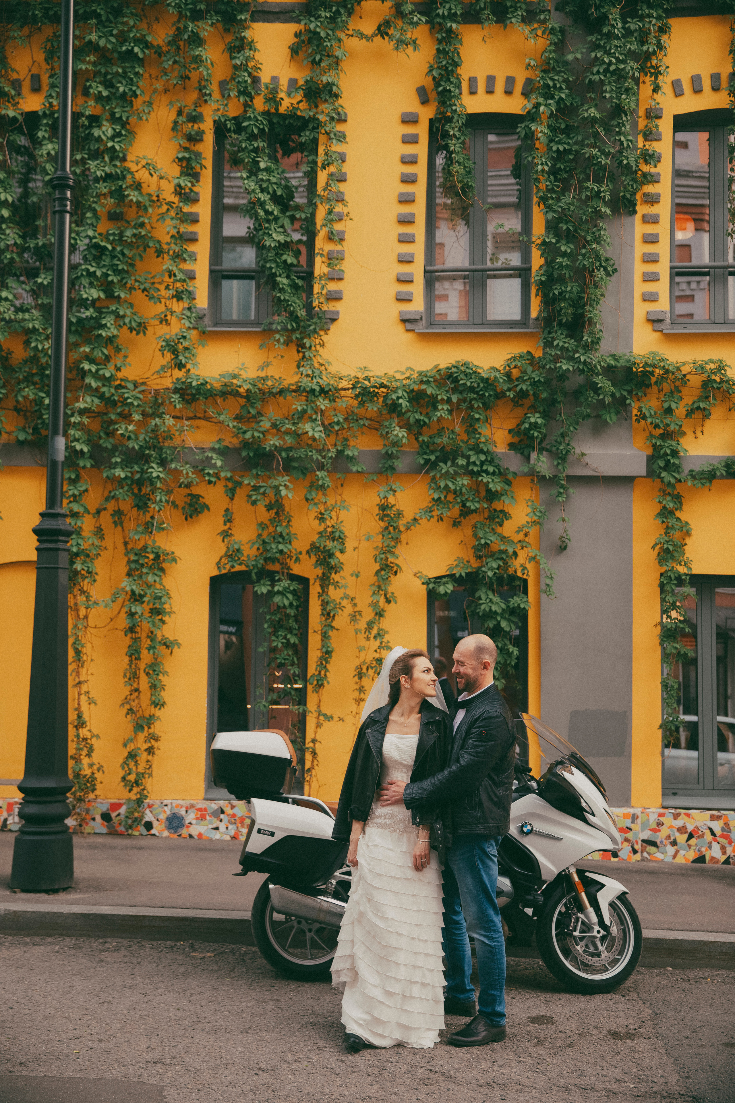 Красивая невеста стоит со своим женихом около своего мотоцикла на улице Трубная 20