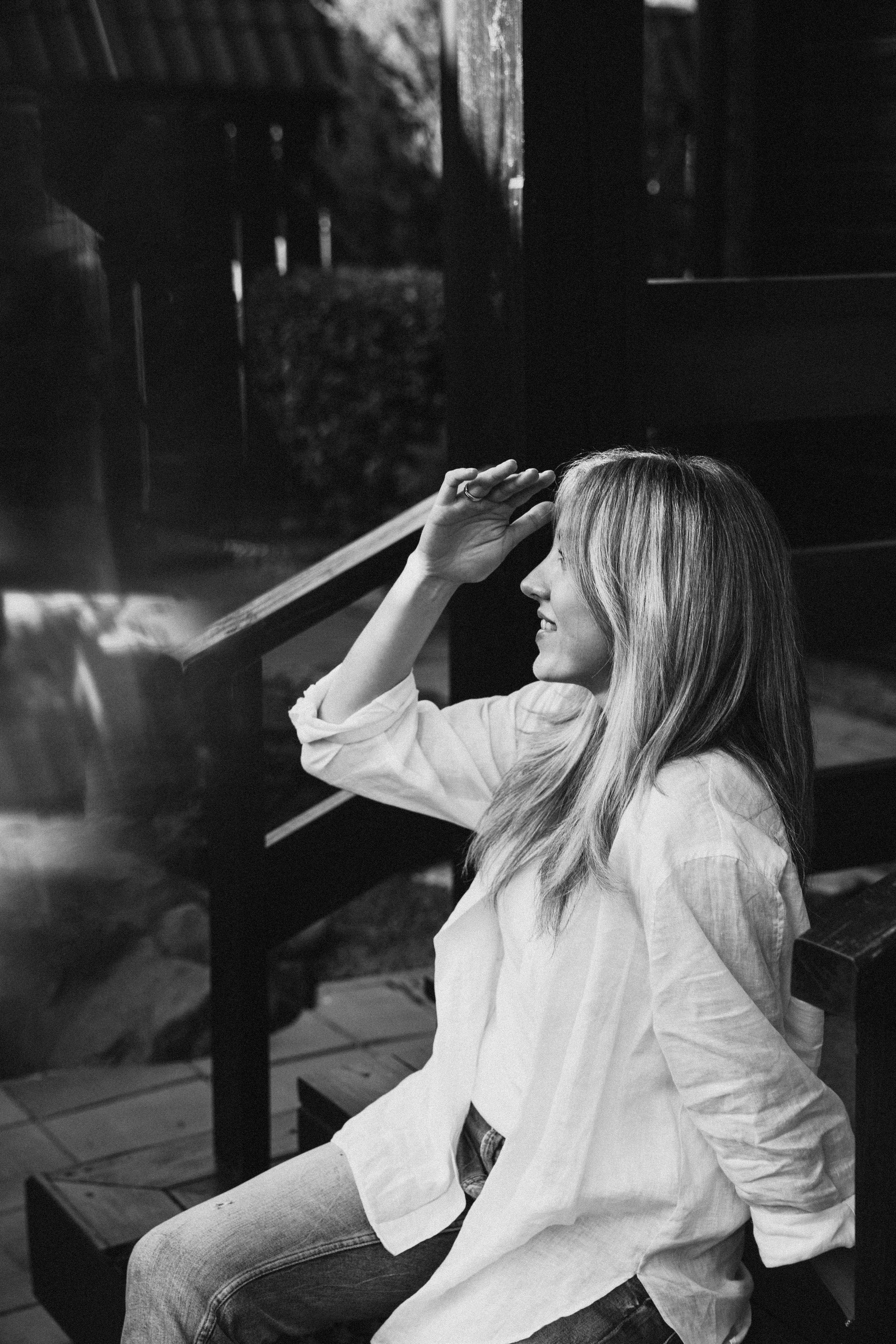 красивая девушка в джинсах и белой майке сидит на ступеньках и улыбается