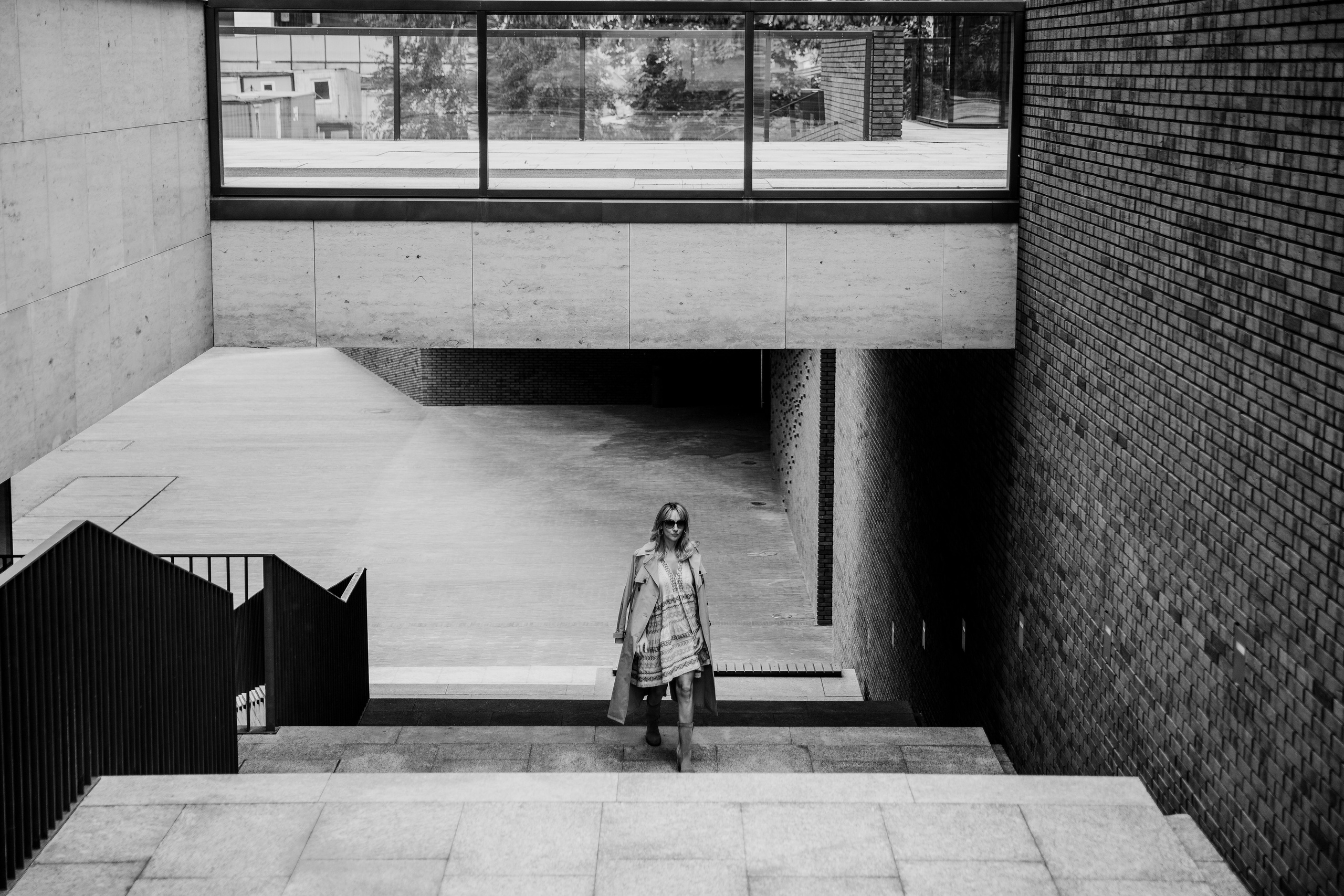 красивая стильная женщина в бежевом тренче идет на роботу поднимаясь по лестнице