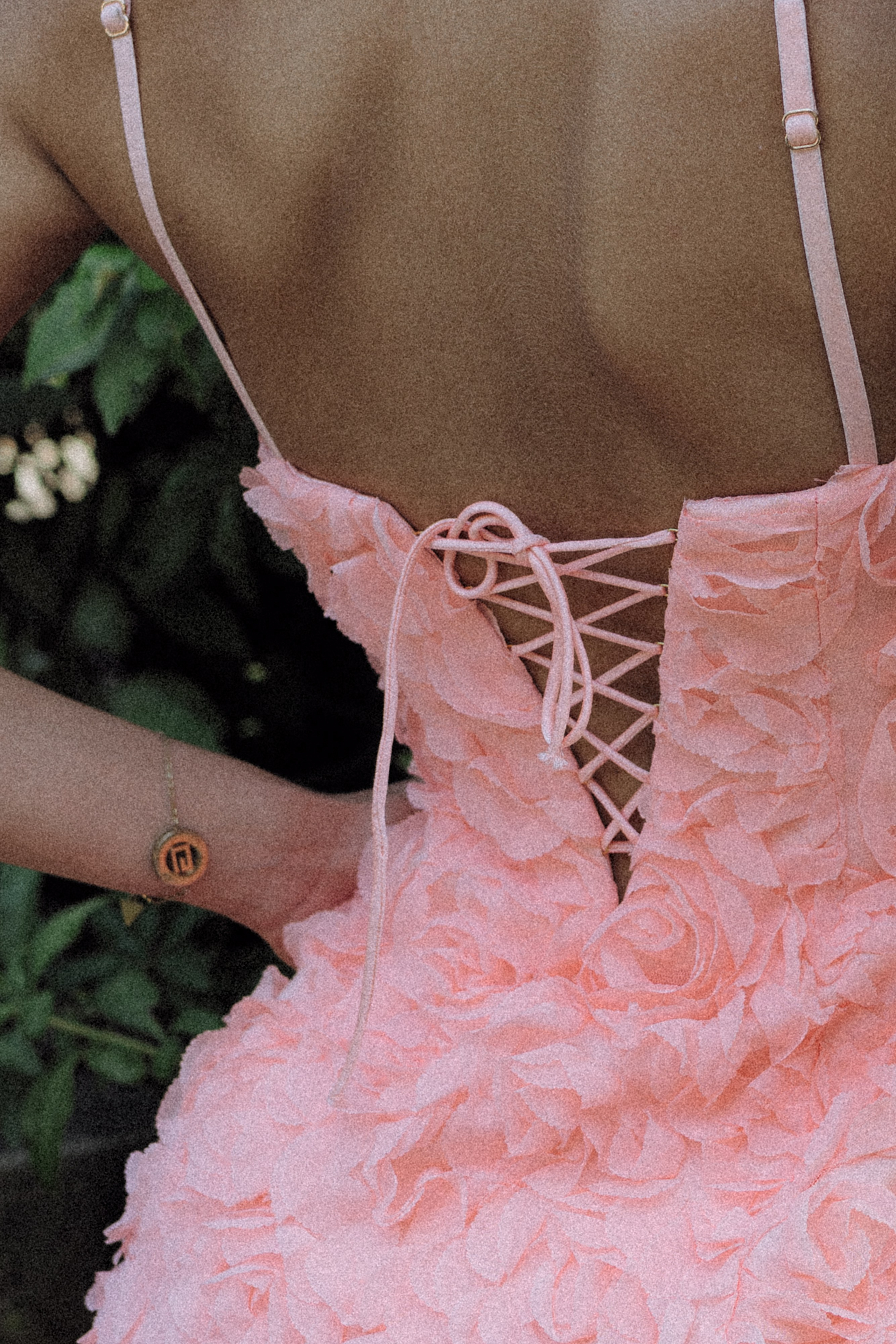 Young woman in a flowing blush dress walking along a tiled Barcelona plaza.