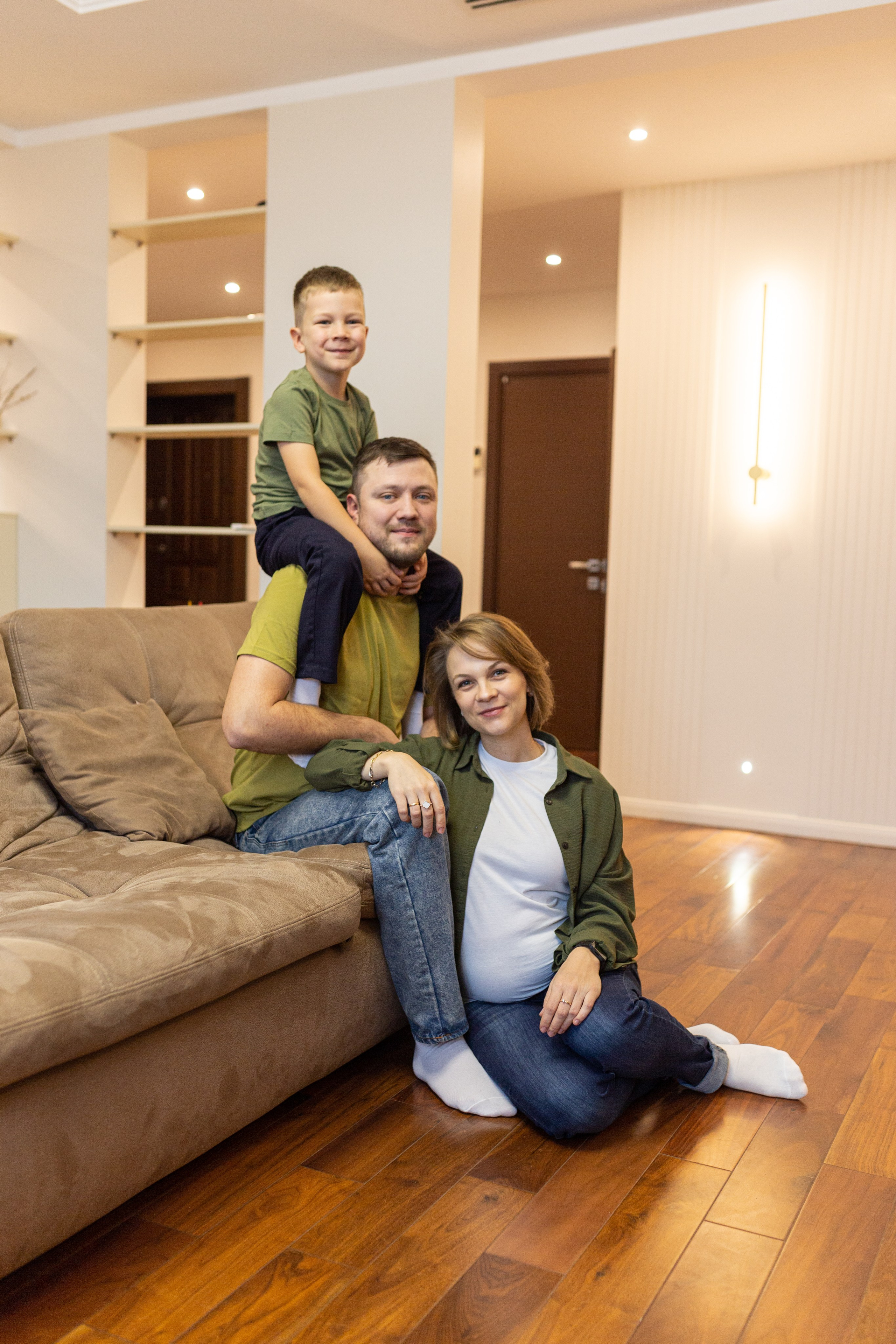 Семья из трех человек в домашней обстановке сидя на диване