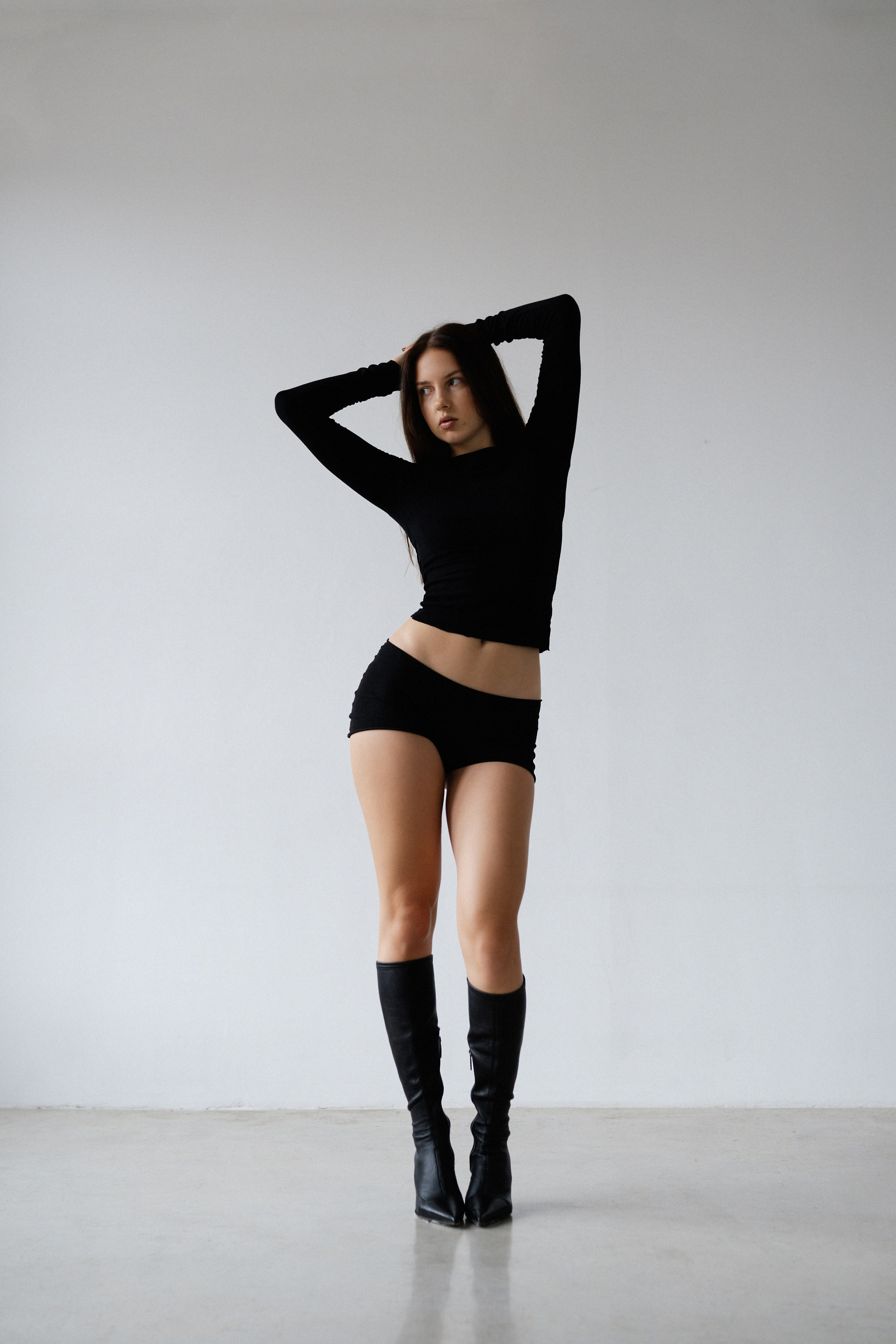 Модель в чёрном топе и шортах позирует в минималистичной студии unity для fashion-фотосессии в Санкт-Петербурге 