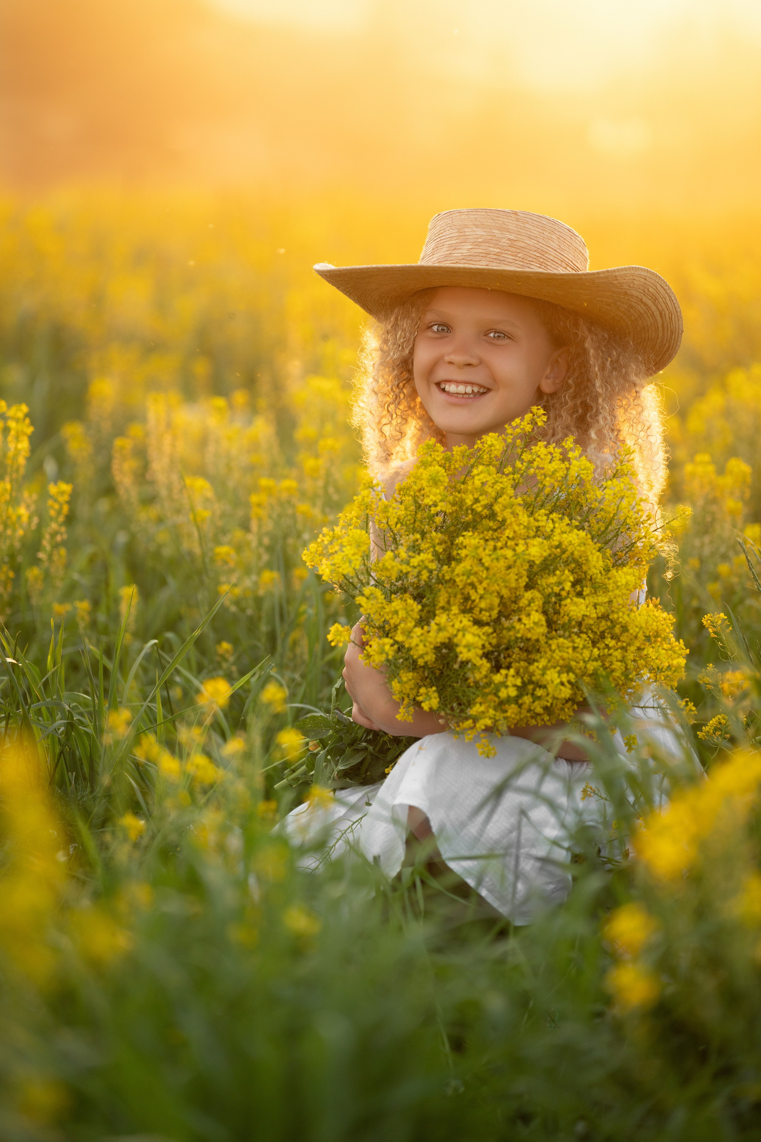 Солнечная девочка в закатных лучах солнца на цветущей поляне.