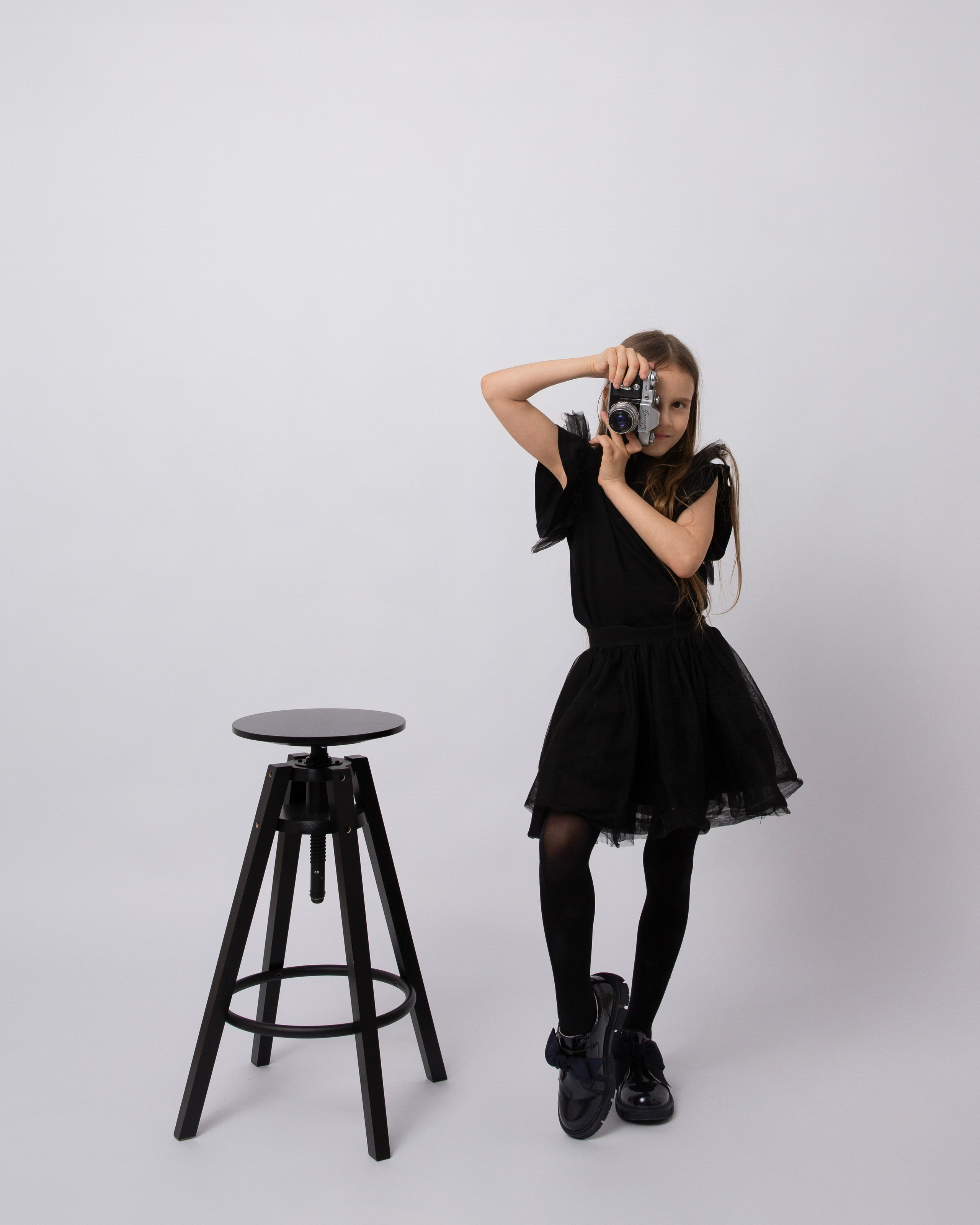 Девочка в черном готическом платье фотографирует на старый фотоаппарт