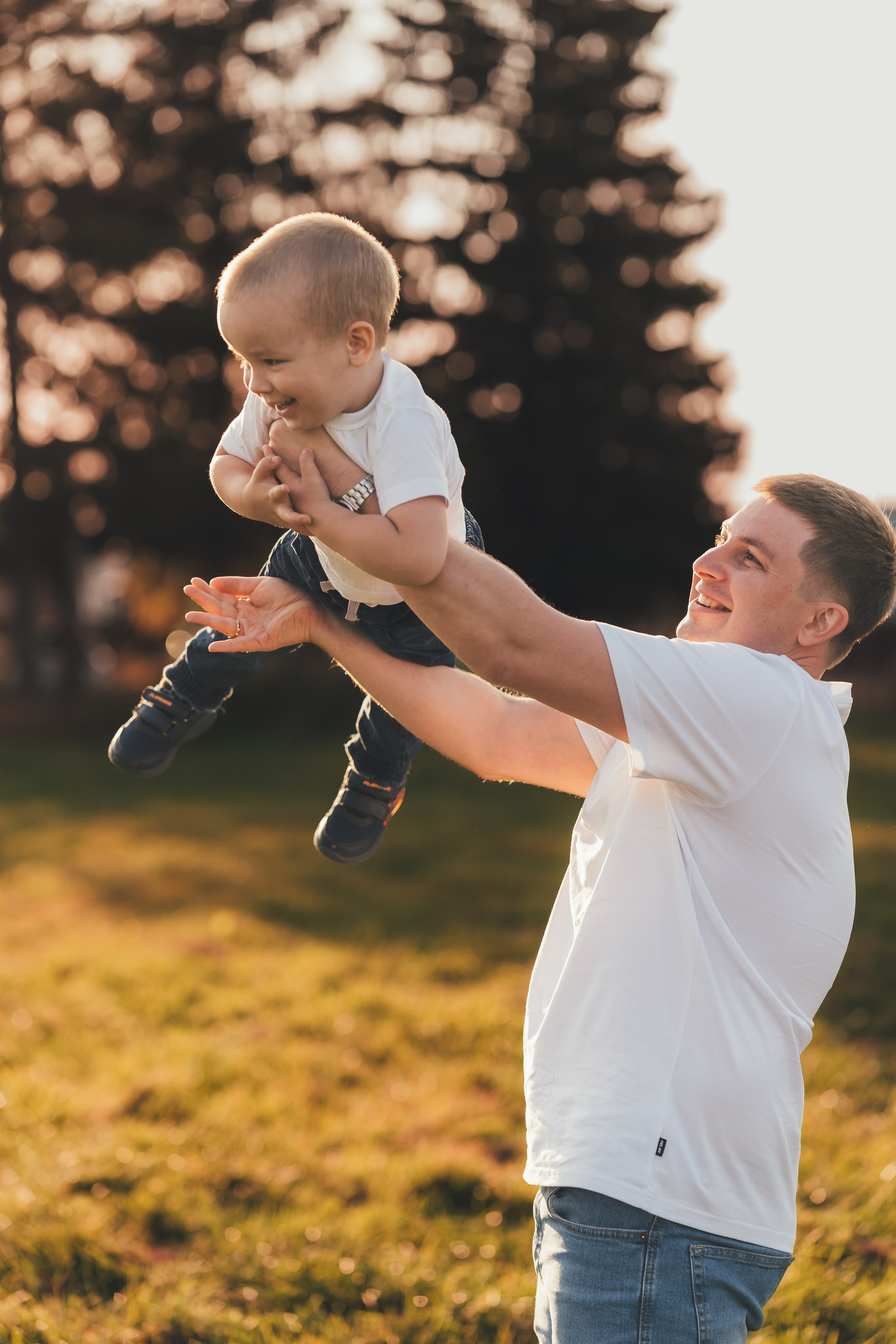 Папа играет с сыном в самолетик, сын смеется