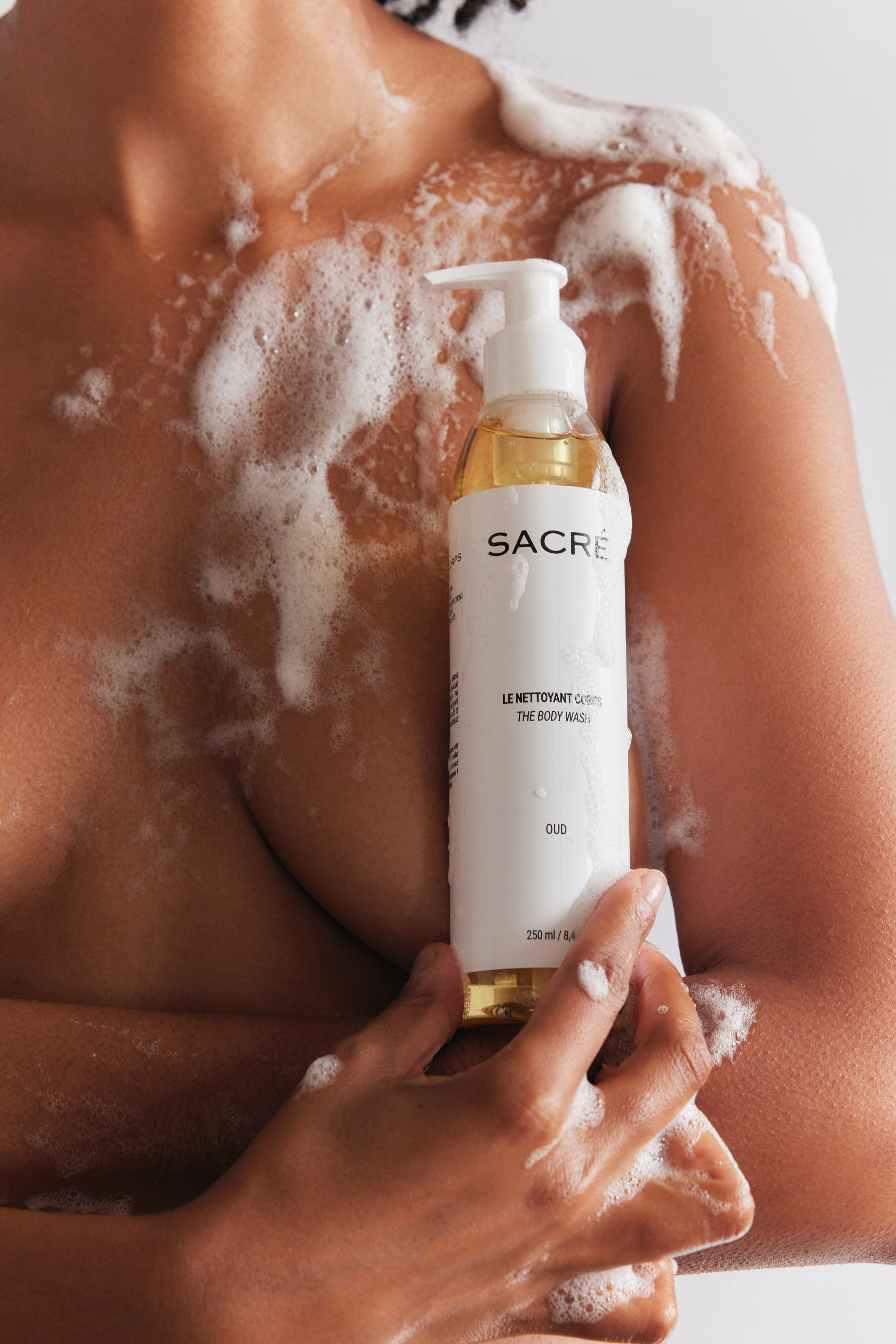 Foamy body wash bottle held by a model, emphasizing a refreshing skincare experience.