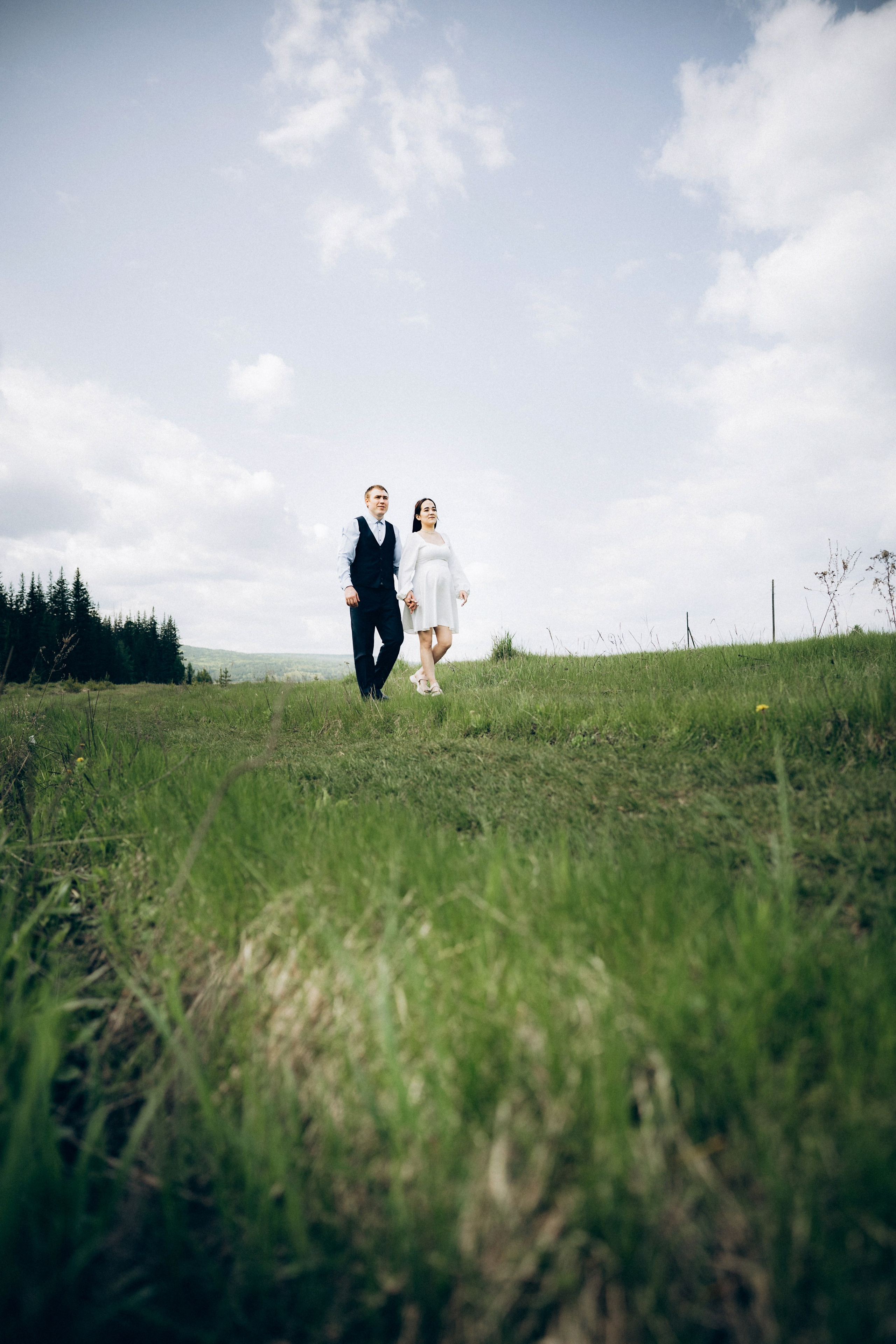 Молодожёны идут по зелёному полю — свадебная прогулка