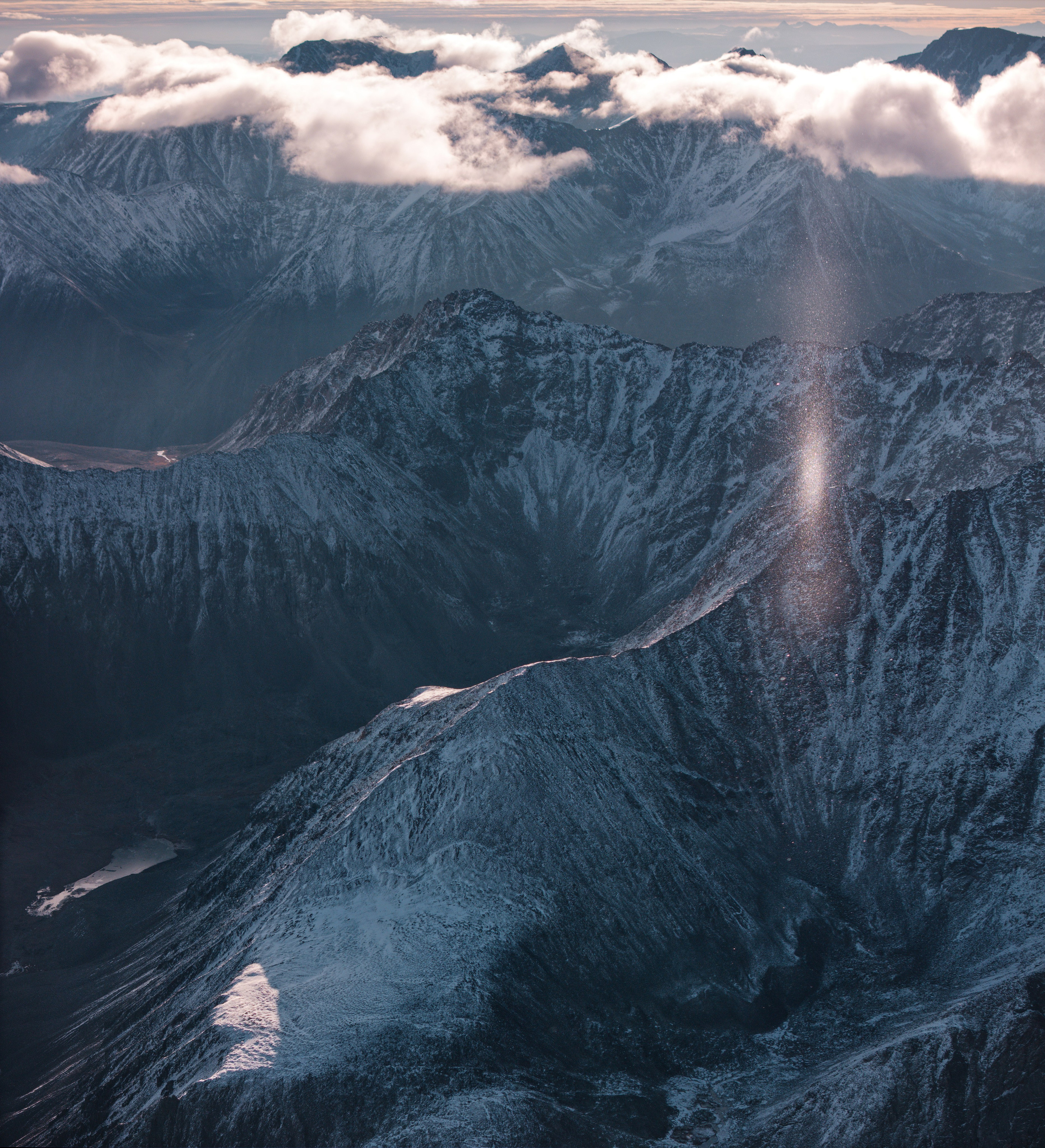 Вид на рассвет над хребтом с узкой полоской облаков и бликом от снега