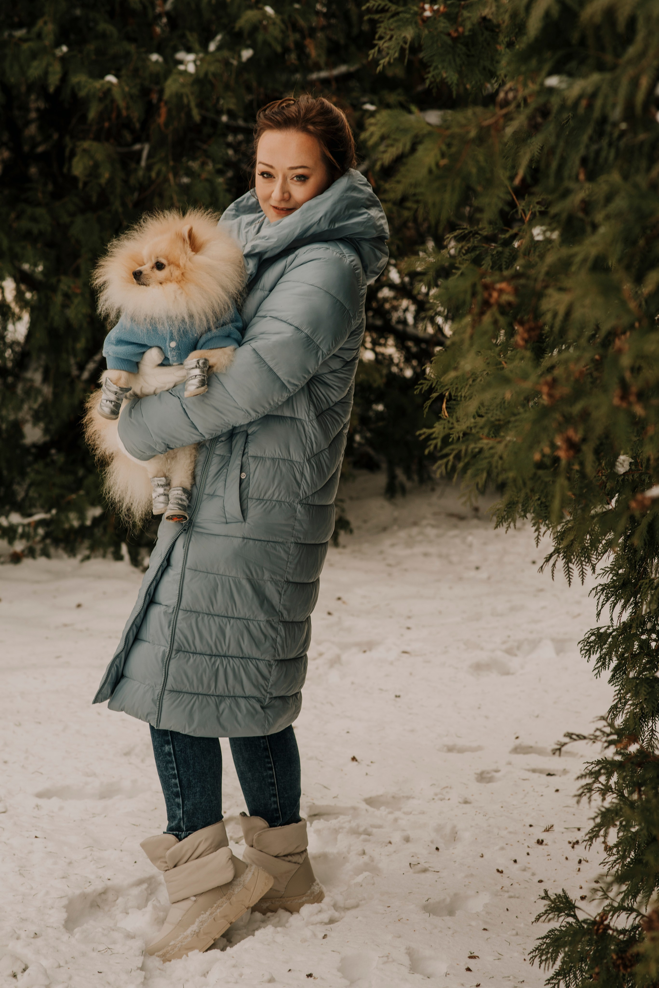 Фотосъемка девушки на фоне вечнозеленых растений со шпицем на руках