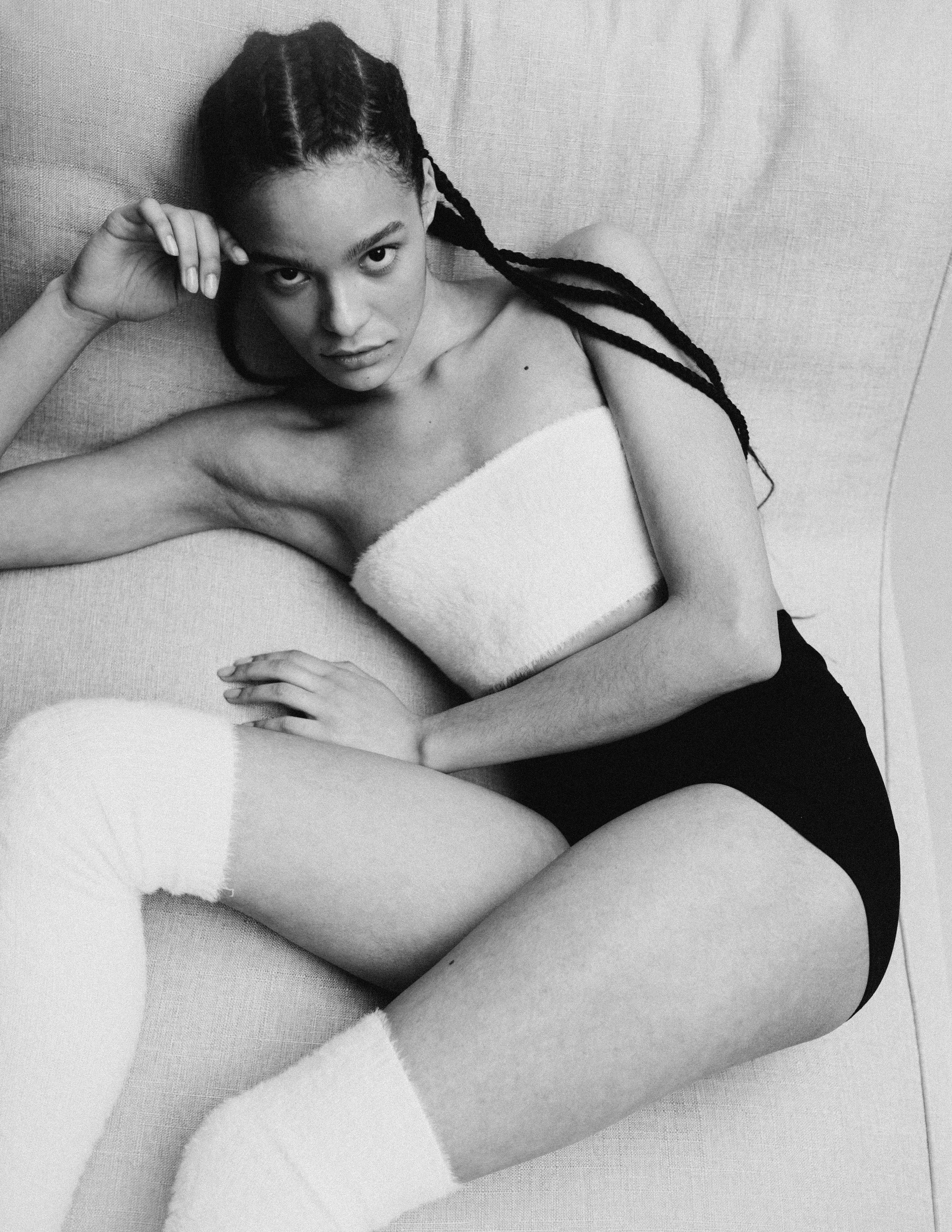 Модель мулатка в пушистом белом топе, пушистых гольфах и коротких шортах.