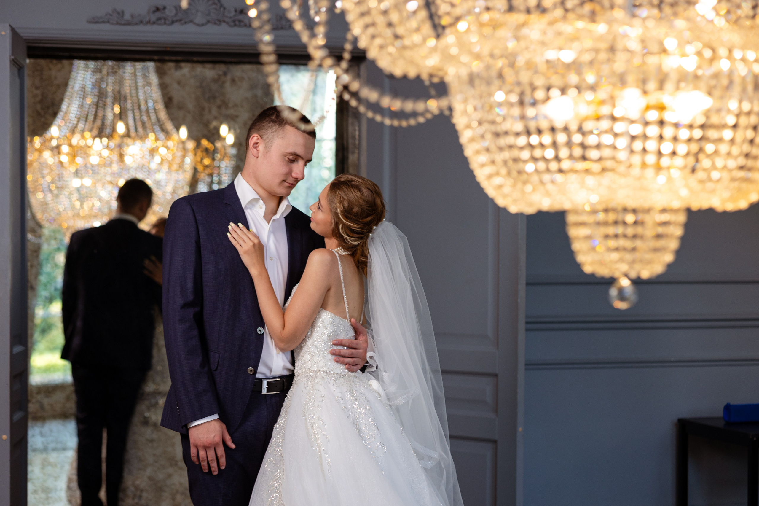 Молодые любуются друг другом на фоне сияющих люстр.