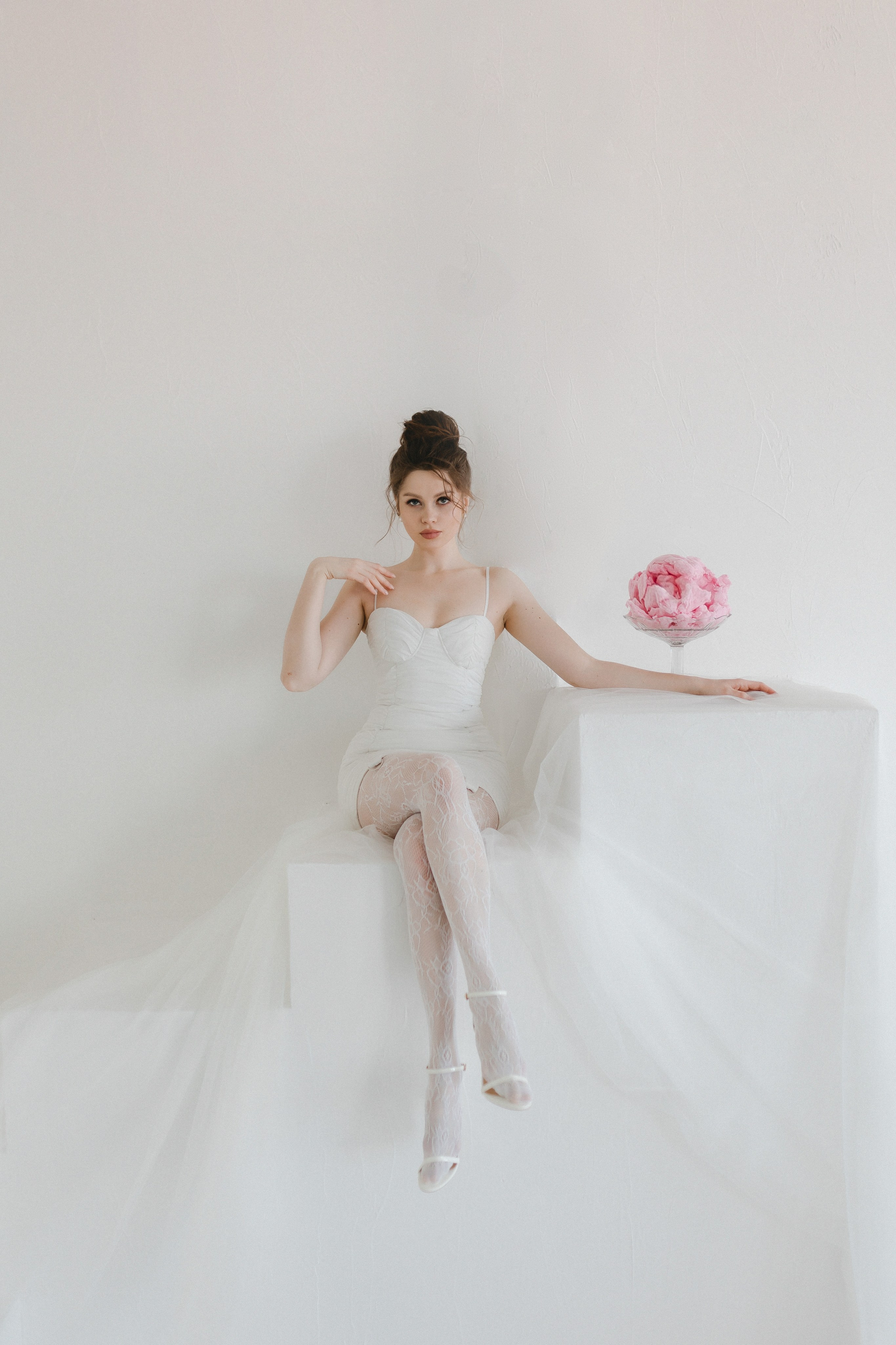 Минималистичный фон подчёркивает изысканный наряд модели