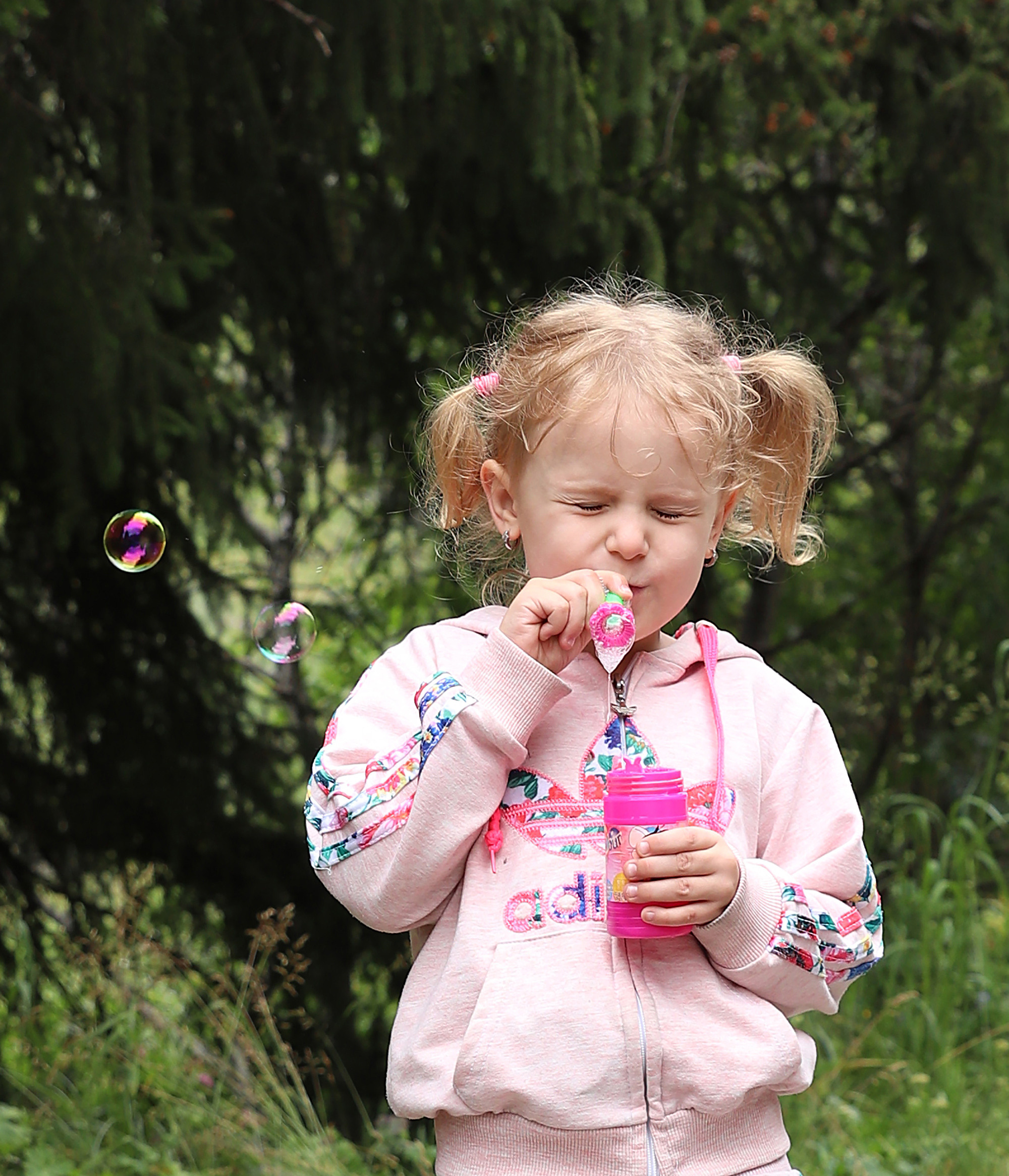 Портрет девочки, выдувающей мыльные пузыри на фоне зеленого леса