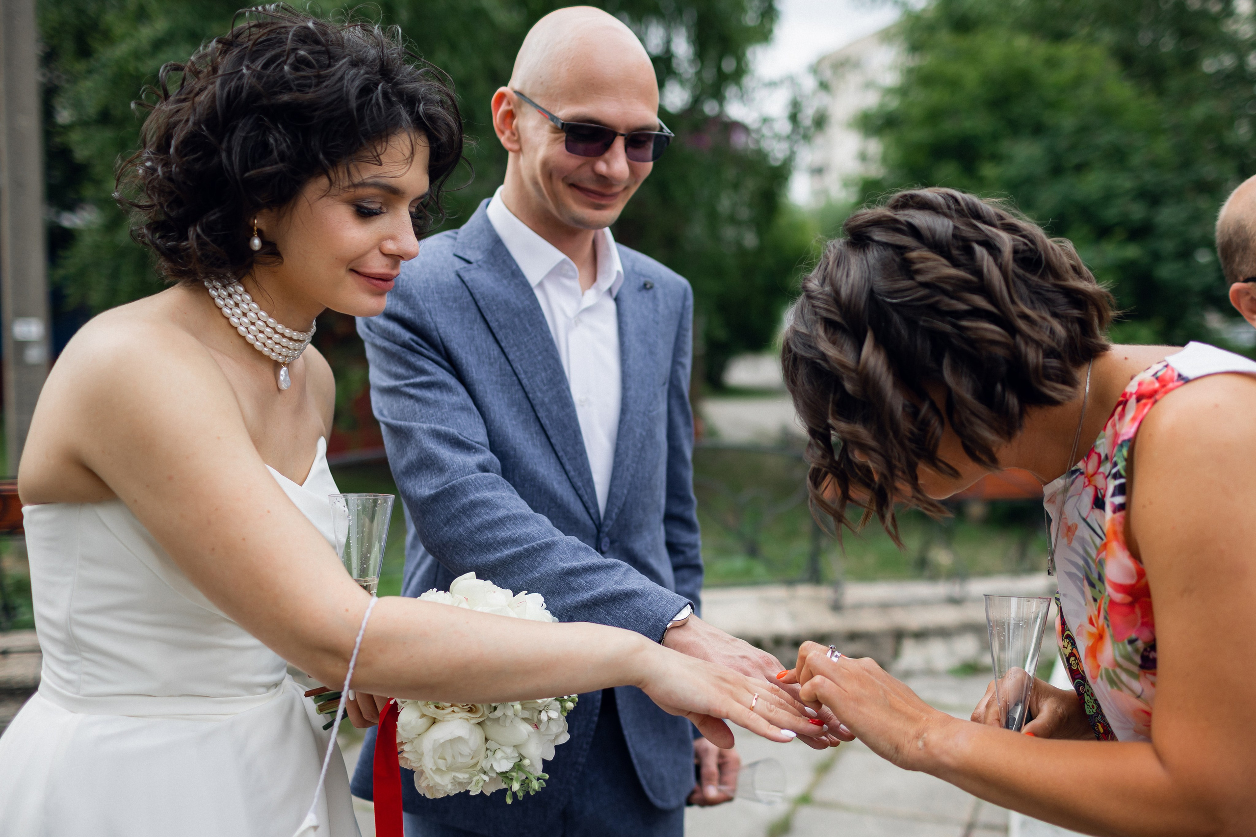 Эмоции первых минут брака: пара в классических костюмах показывает гладкие обручальные кольца