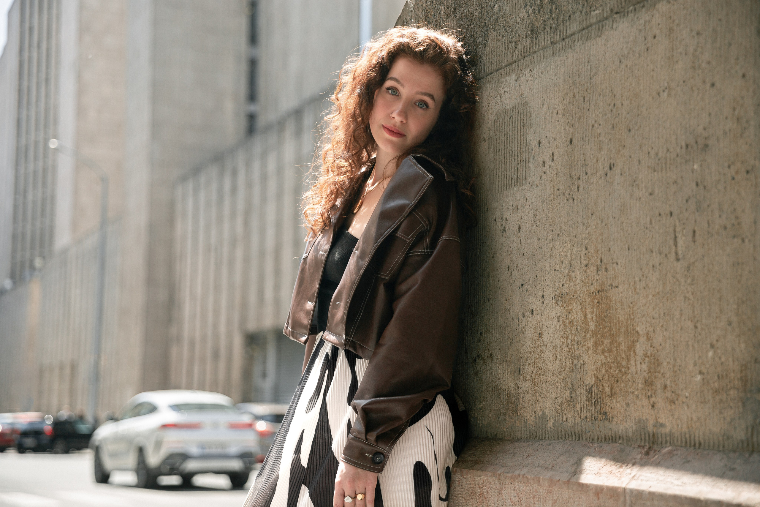 a photo of a girl on the streets of Budapest, with a silver car in the background