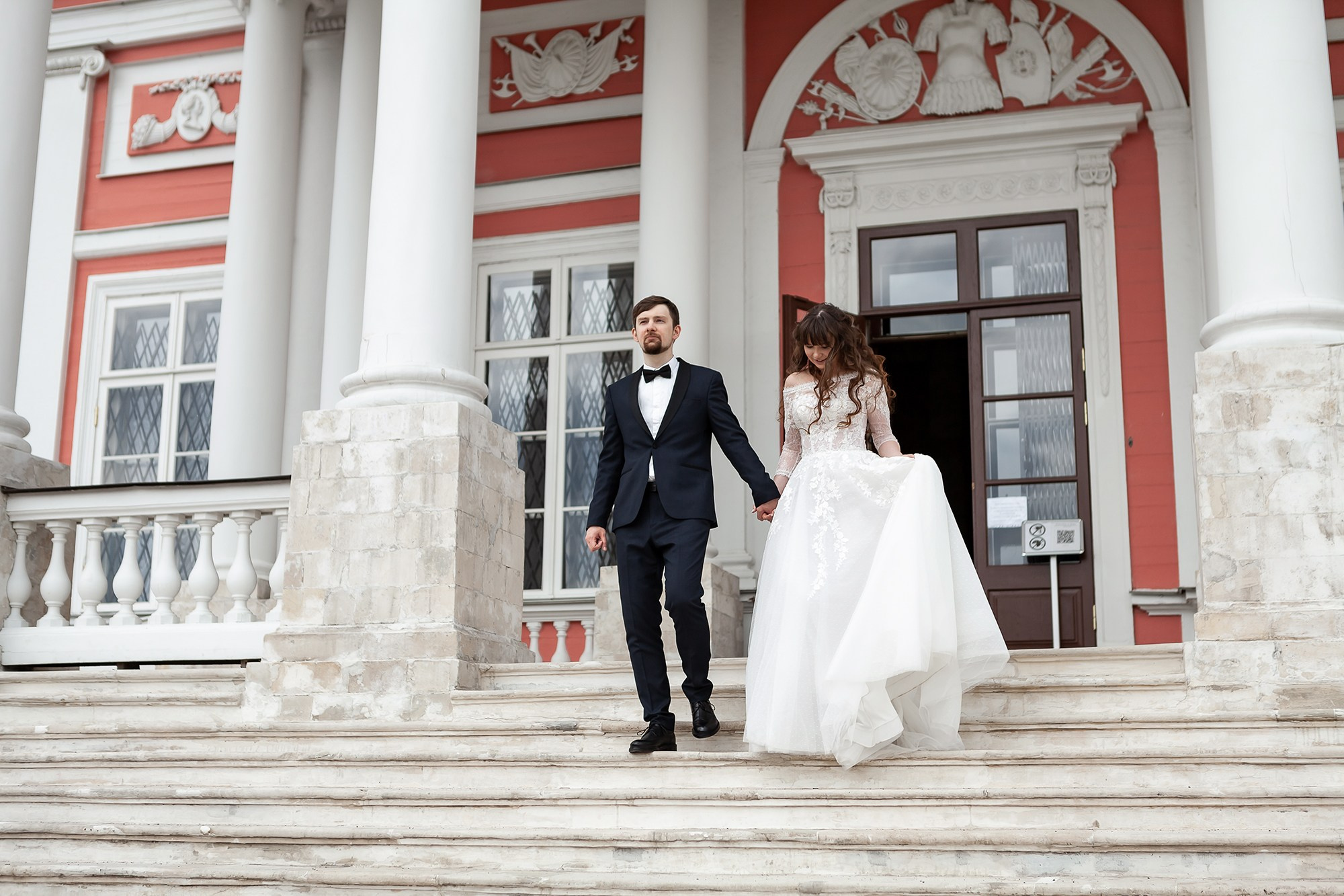 Жених помогает невесте спуститься по лестнице