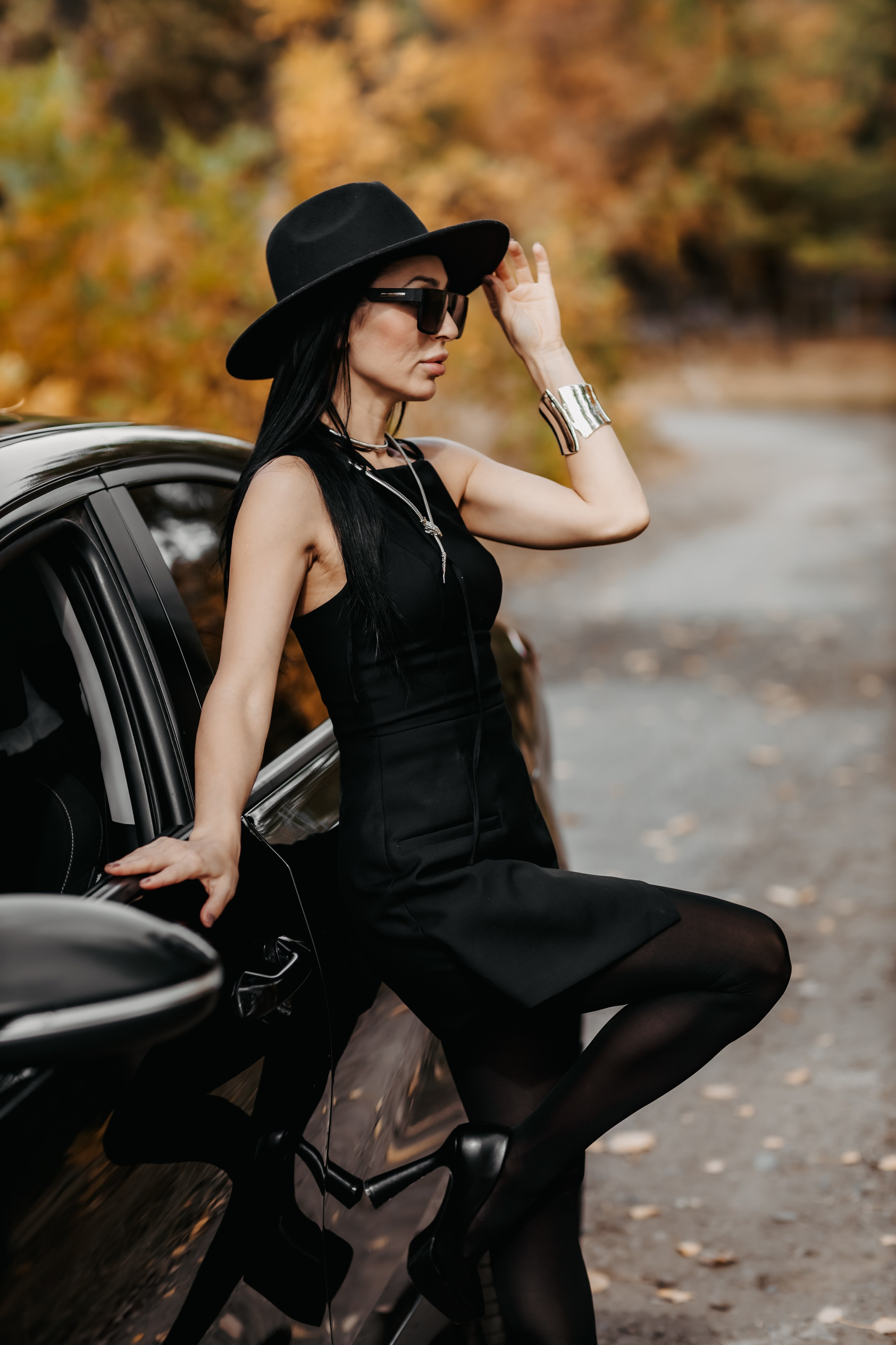 Очарование осени: девушка на фоне стильной машины под яркими деревьями