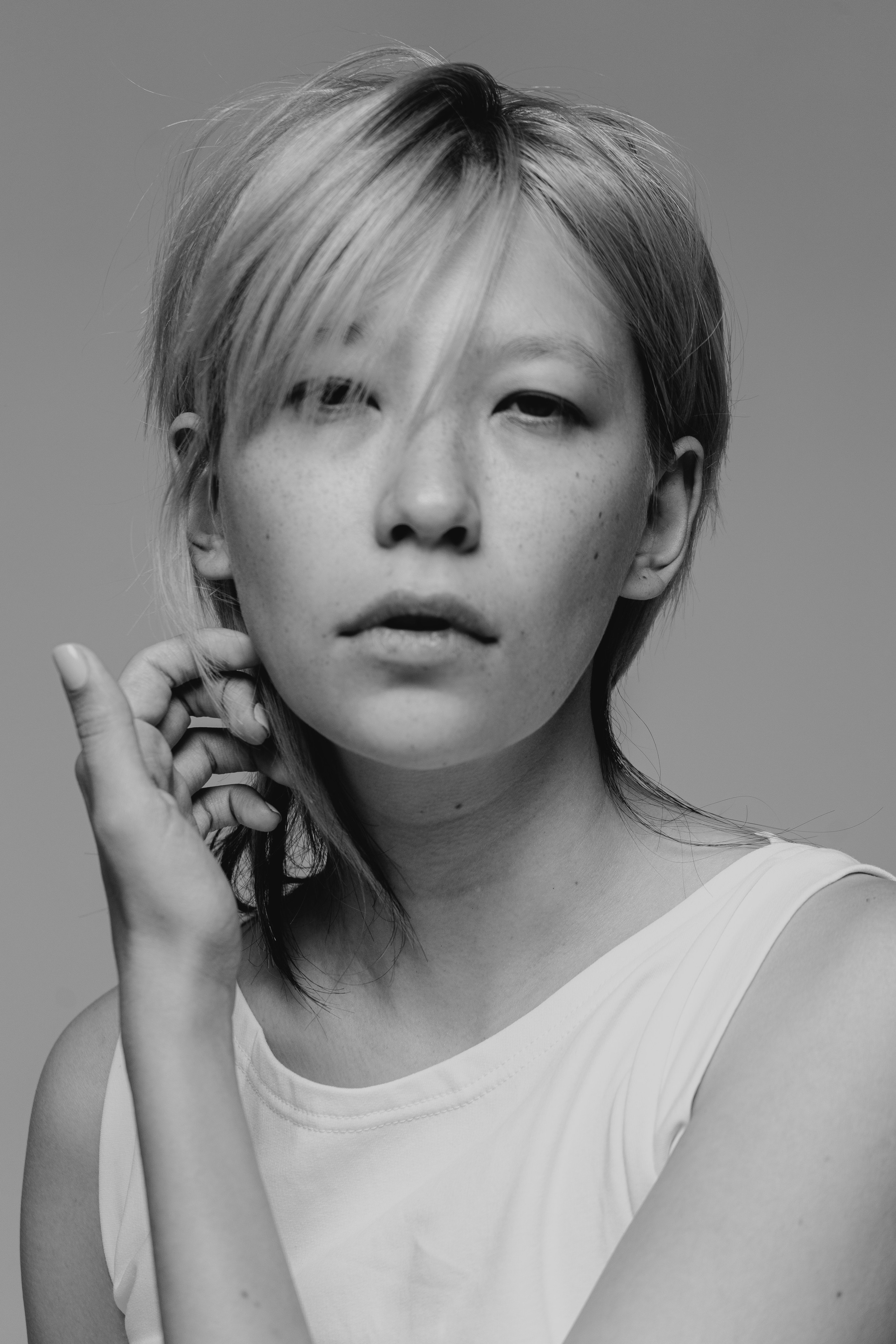 Модель смотрит на фотографа, приподнимая руку к лицу