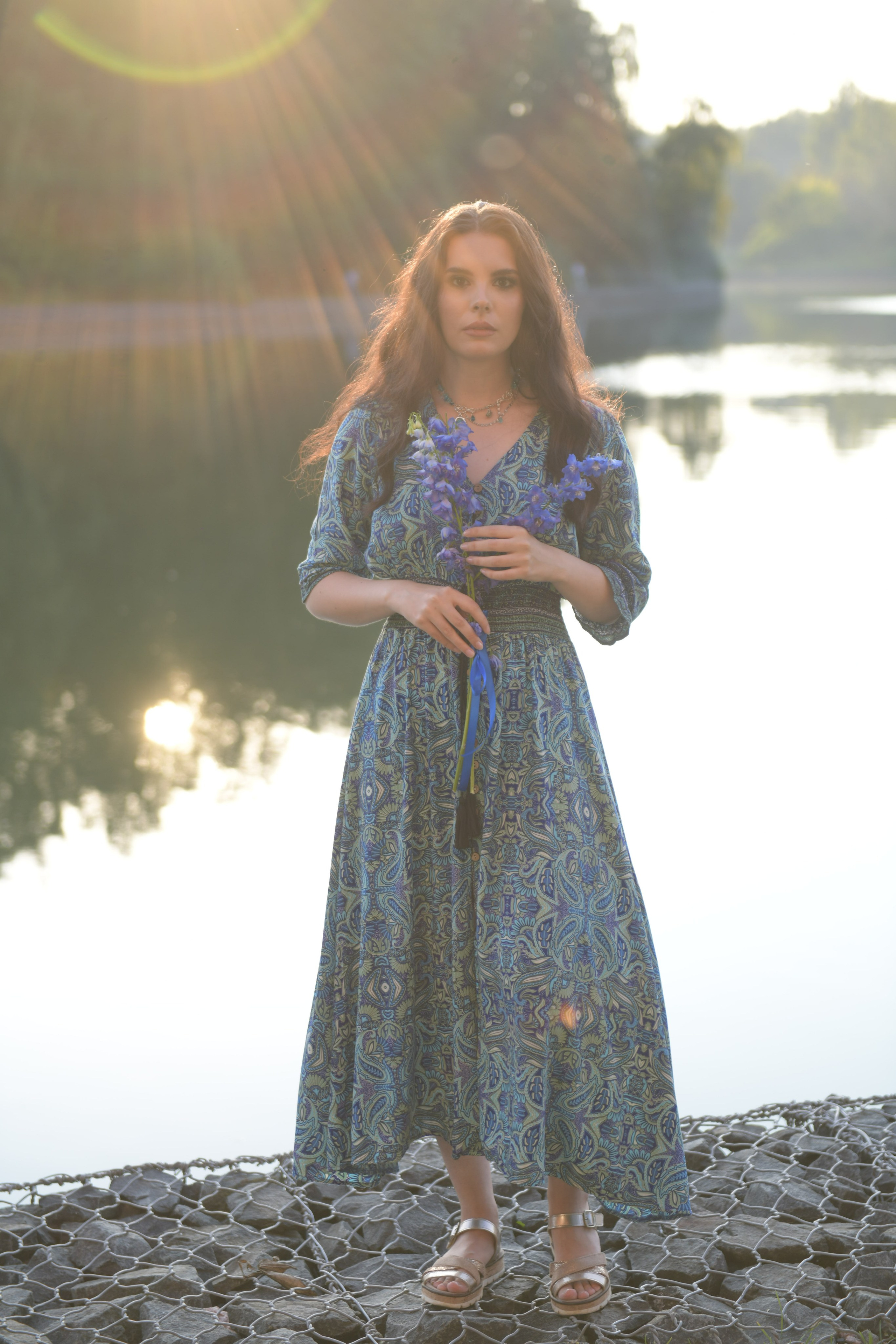 Девушка на фоне озера в закатном свете.