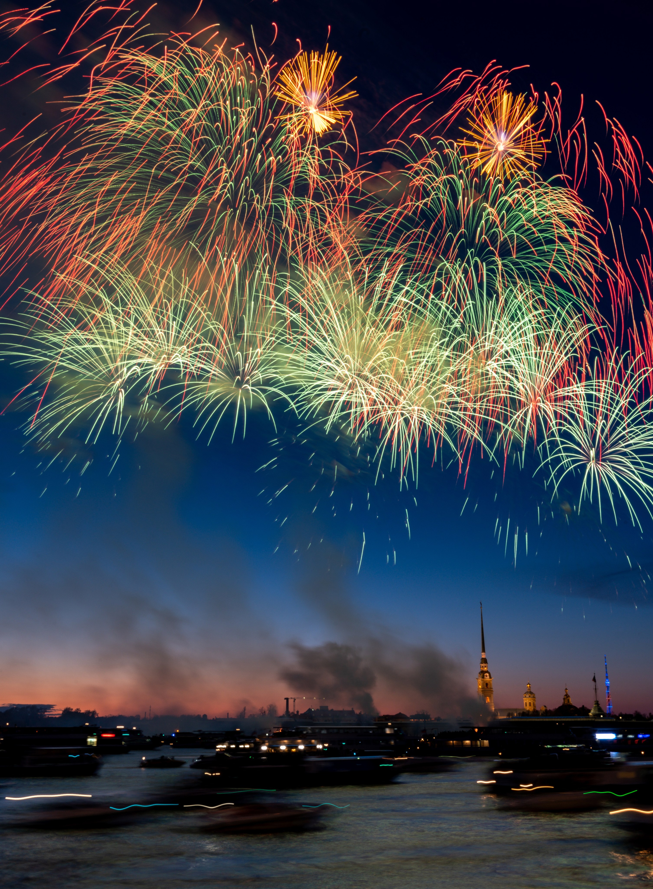 Фейерверк над Невой в Санкт-Петербурге, вспышки разноцветных огней на фоне Петропавловки и дымки, атмосферная ночная фотография.