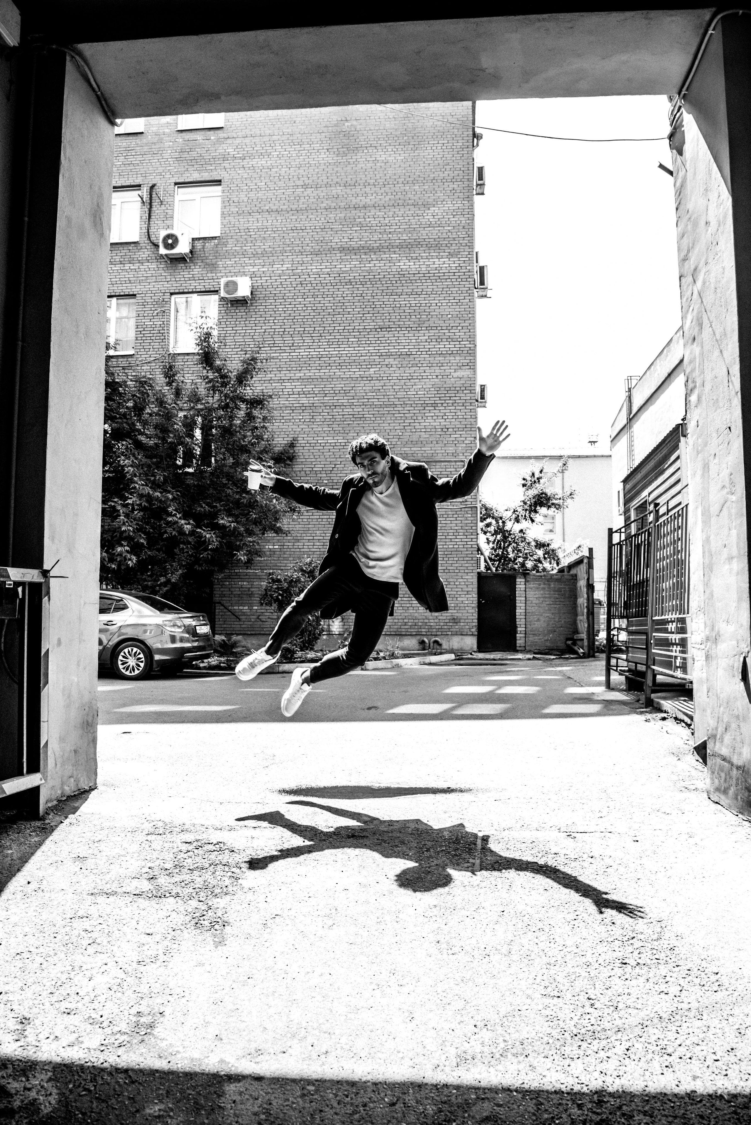 парень в прыжке в арке здания