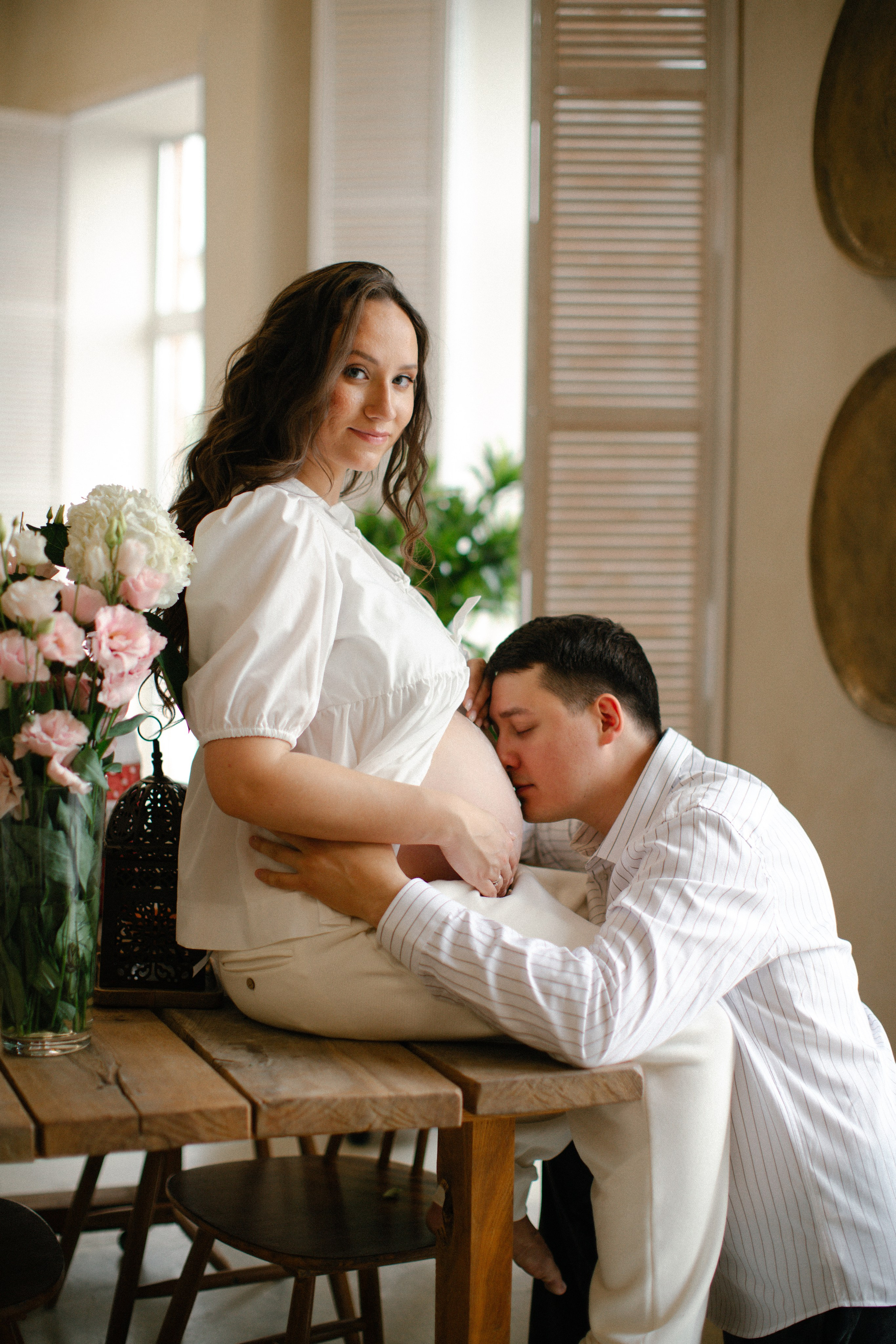 беременная на столе, будущий папа целует живот, фотосессия беременности